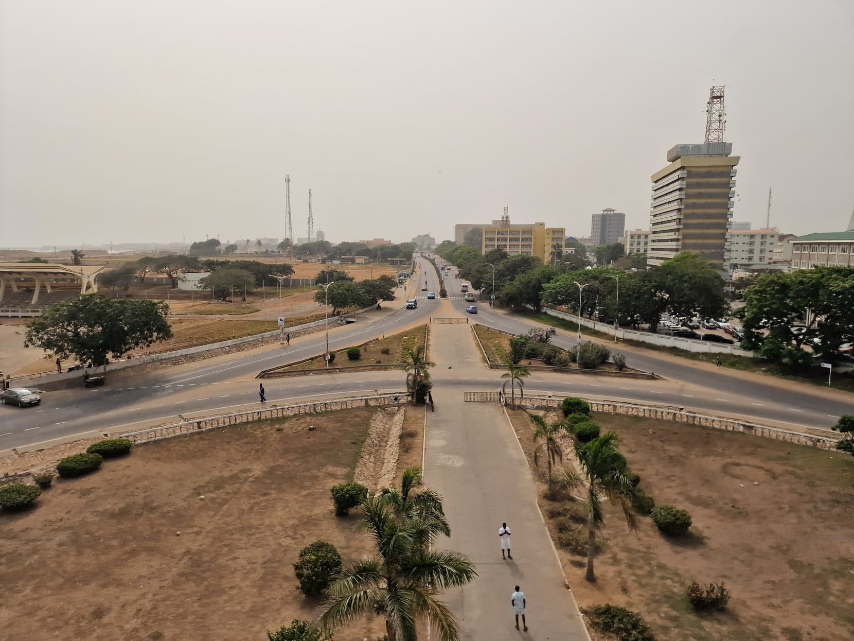 A wide divided boulevard running toward tower blocks in harmattan haze, Accra, Ghana