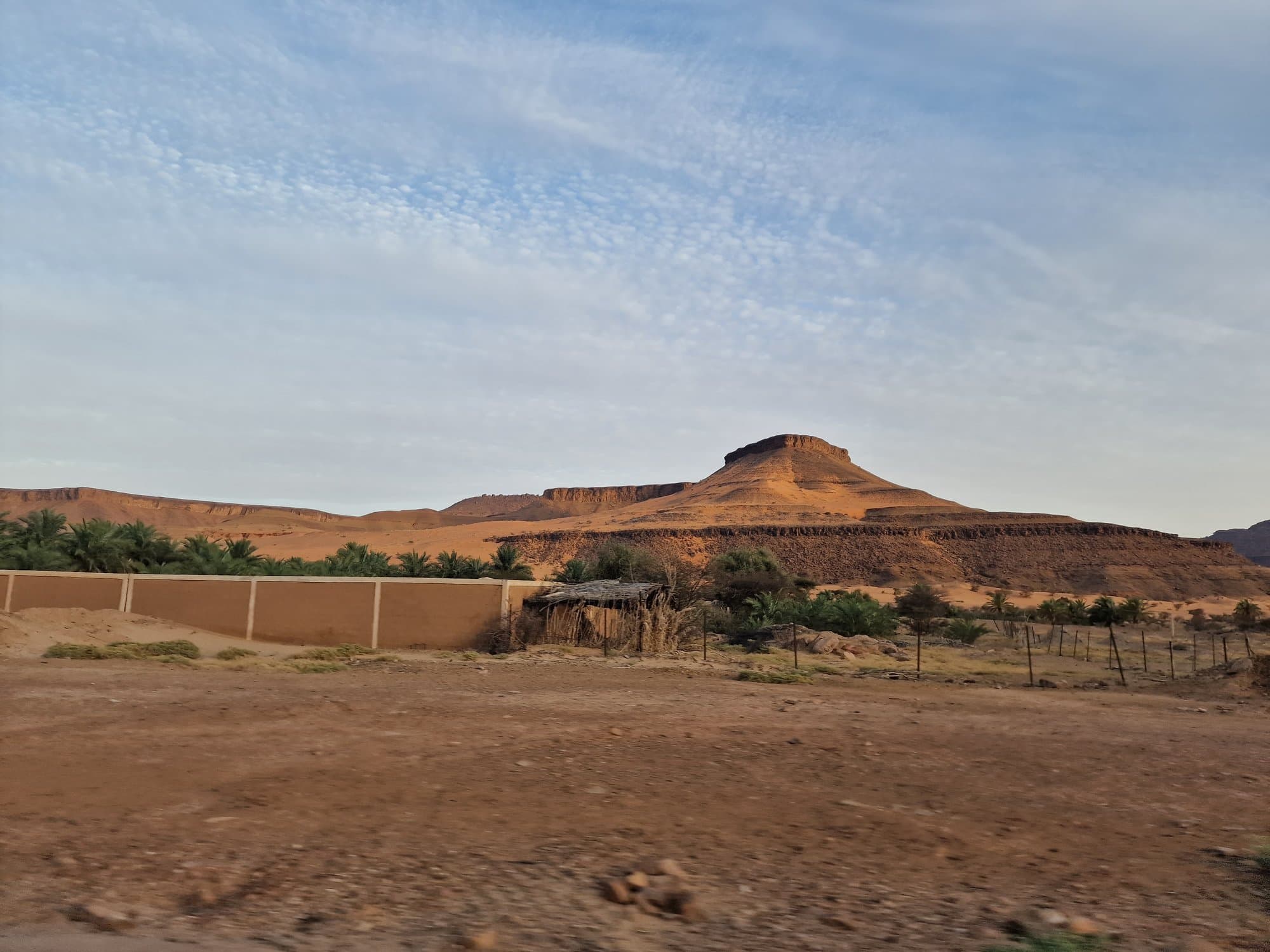 The sun setting behind a flat-topped mesa in the Adrar