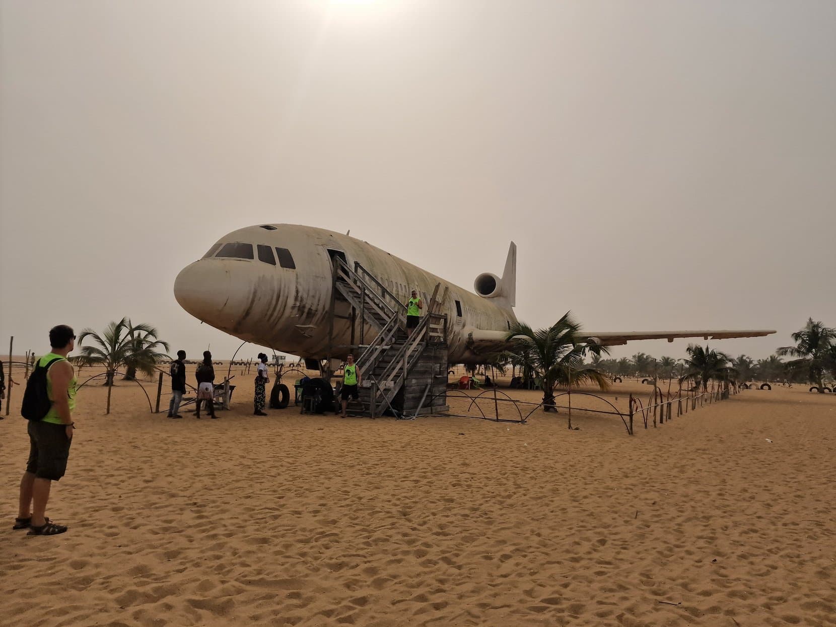 A three-engined airliner parked on the sand with a boarding staircase at its door and palms behind, on the beach west of Cotonou, Benin