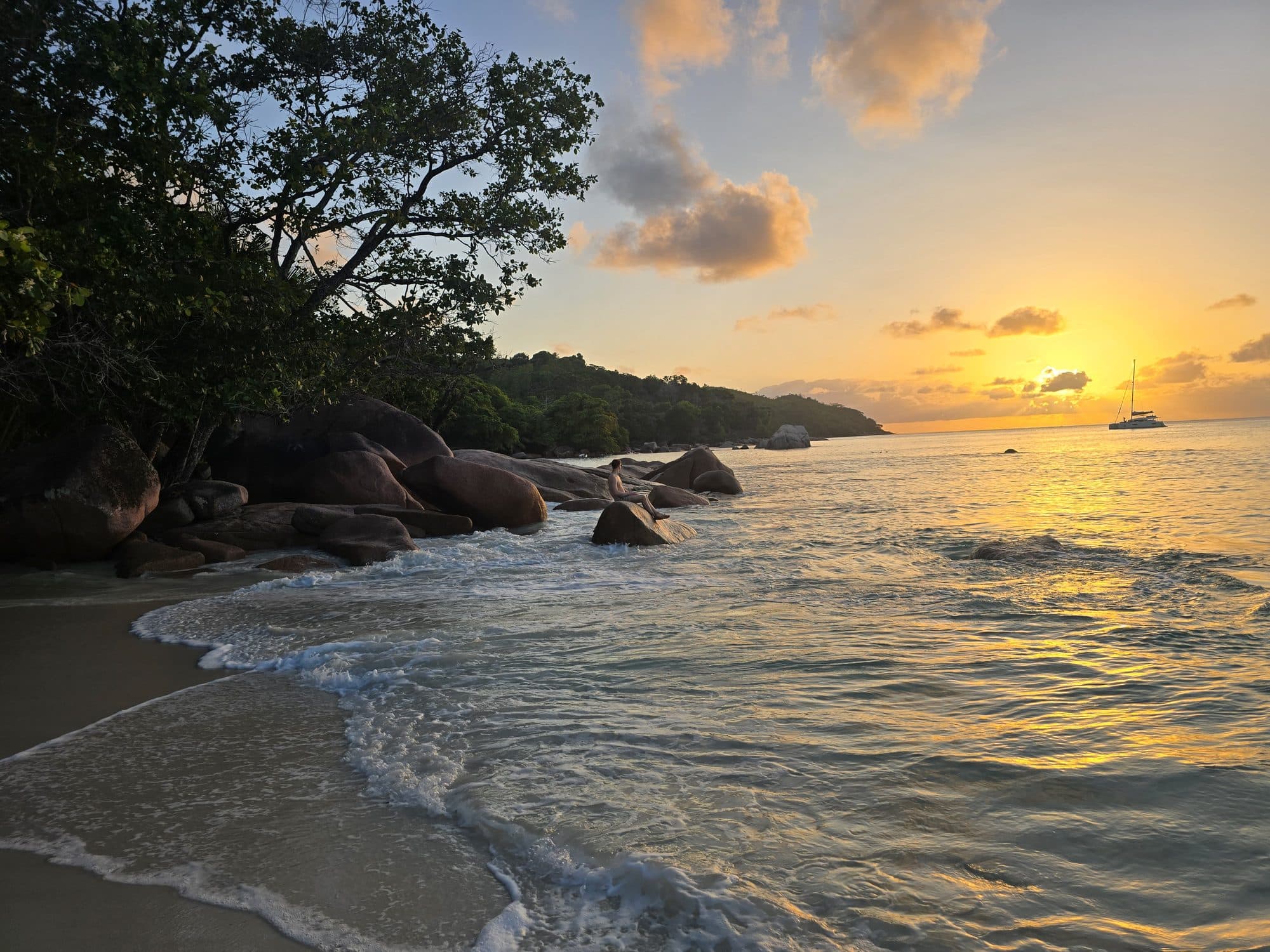 Sunset over the water and granite boulders at Anse Georgette, Praslin, Seychelles