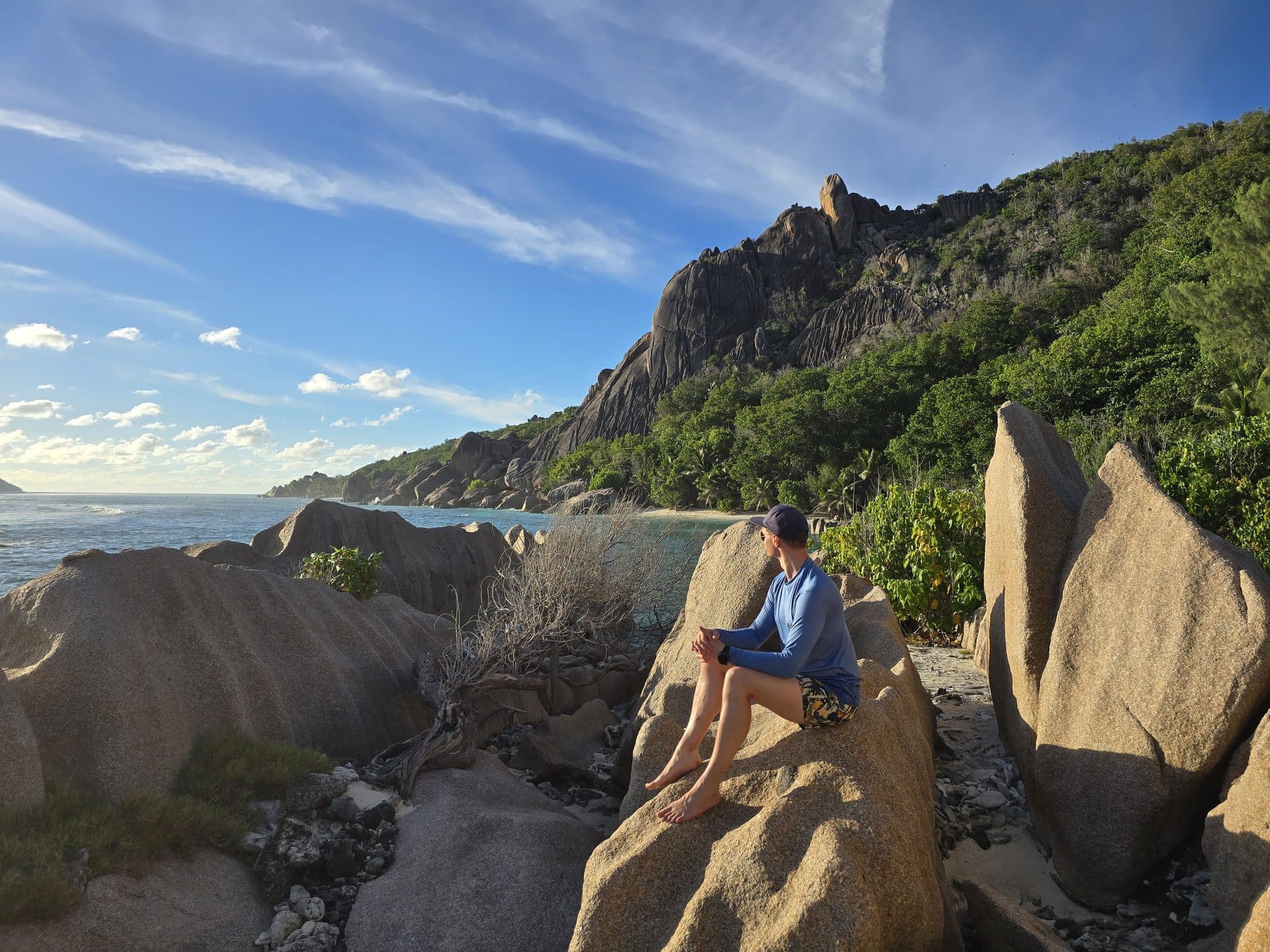 Sitting on granite boulders on the wild coast at Anse Pierrot, La Digue, Seychelles
