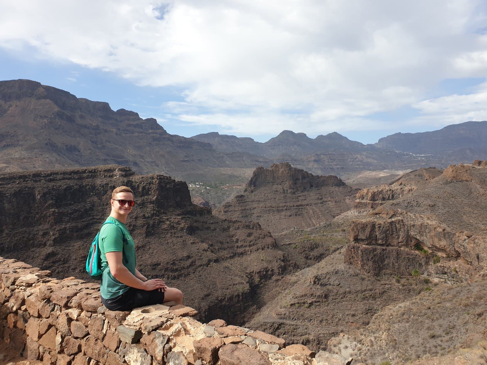 The founder sitting on a stone wall above a barranco panorama, Gran Canaria