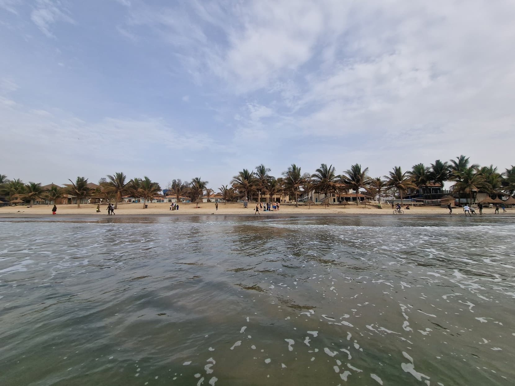Palm-lined beach seen from the surf on The Gambia's Atlantic coast