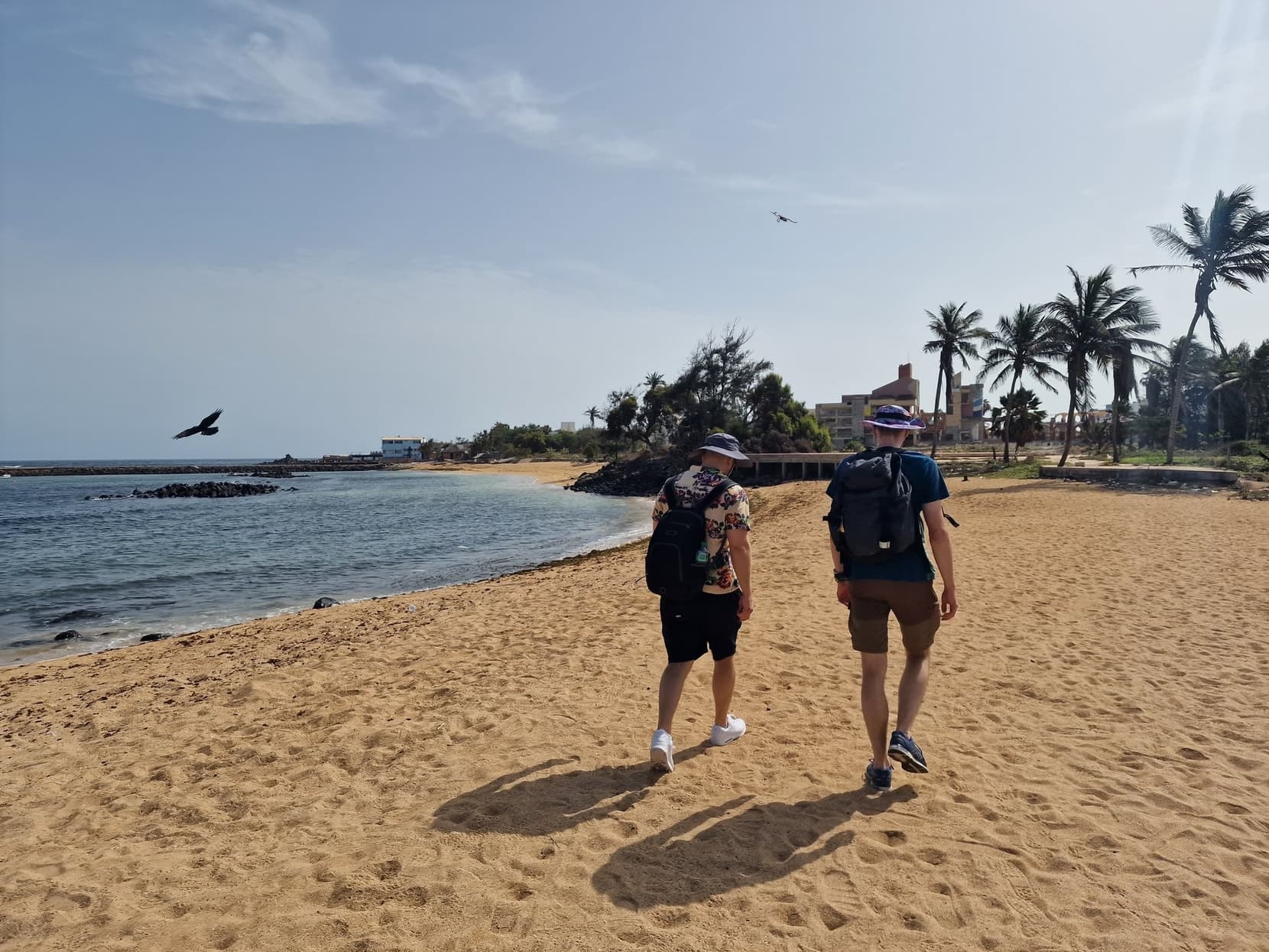 Two travellers walking a sandy beach on the Dakar coast