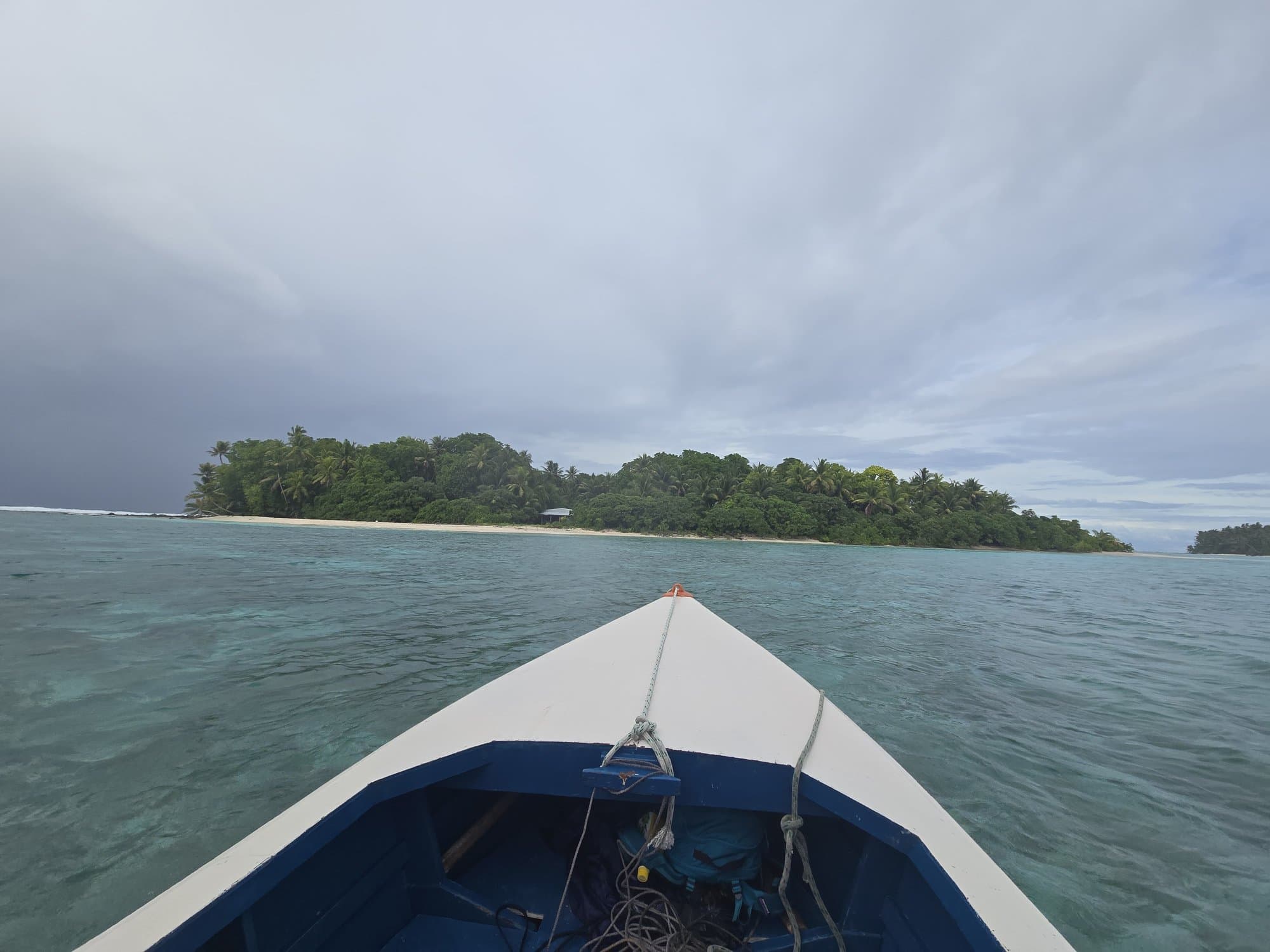 The bow of an open boat pointed at a lagoon islet