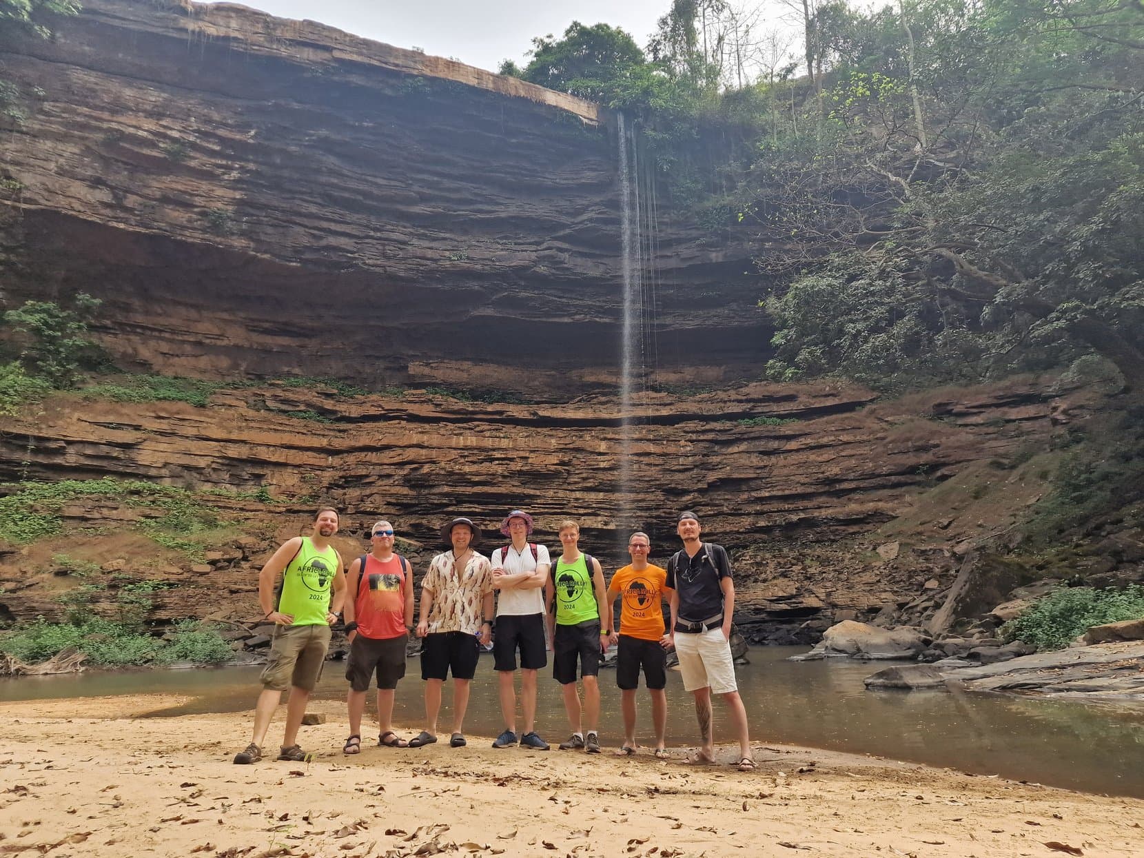 The rally crew standing on the dry sandy floor of the Boti gorge below a thin thread of water, Ghana