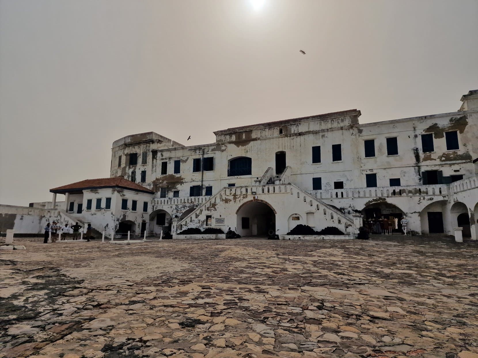 The whitewashed courtyard and upper storeys of Cape Coast Castle under a hazy sky, Ghana