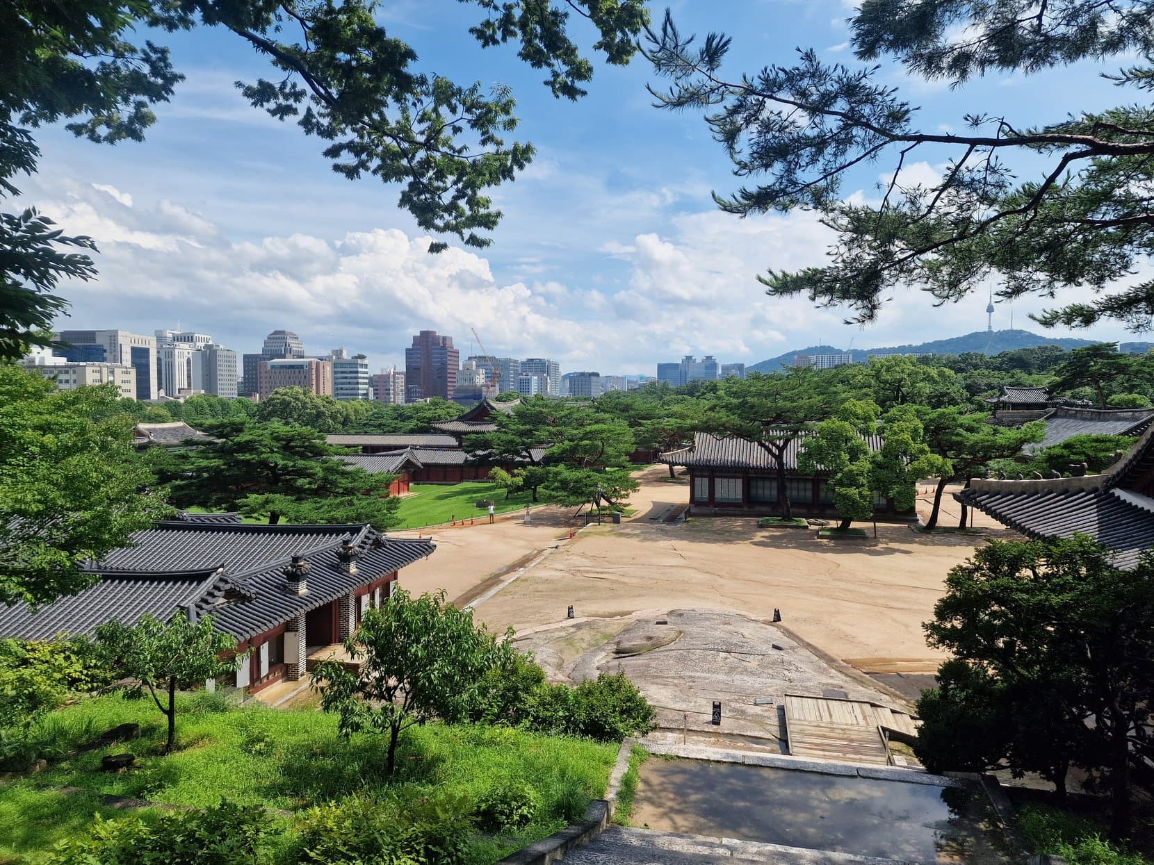 The tiled roofs of Changdeokgung palace with Seoul's office towers rising behind them
