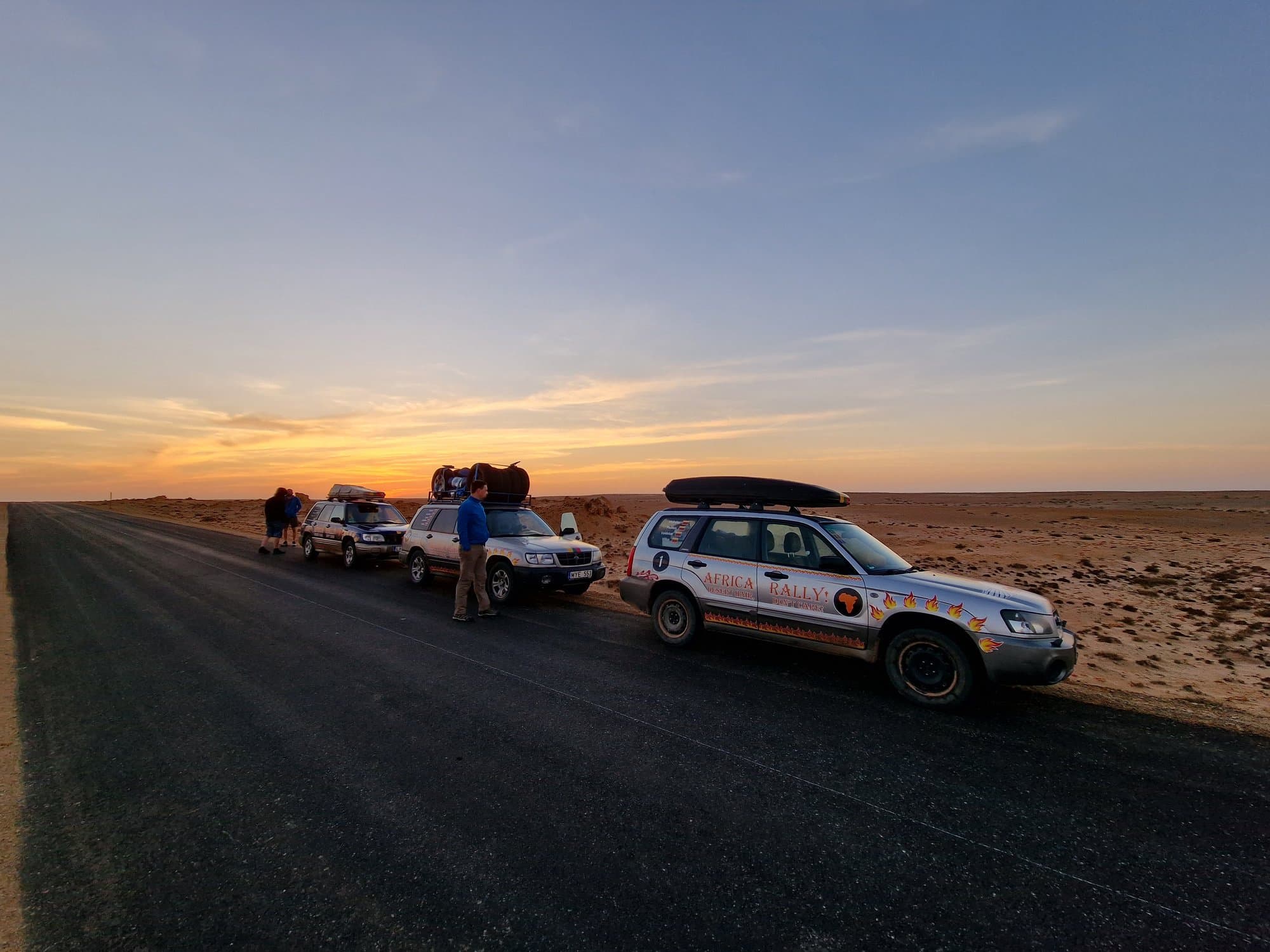 The rally convoy parked on the highway shoulder at dawn