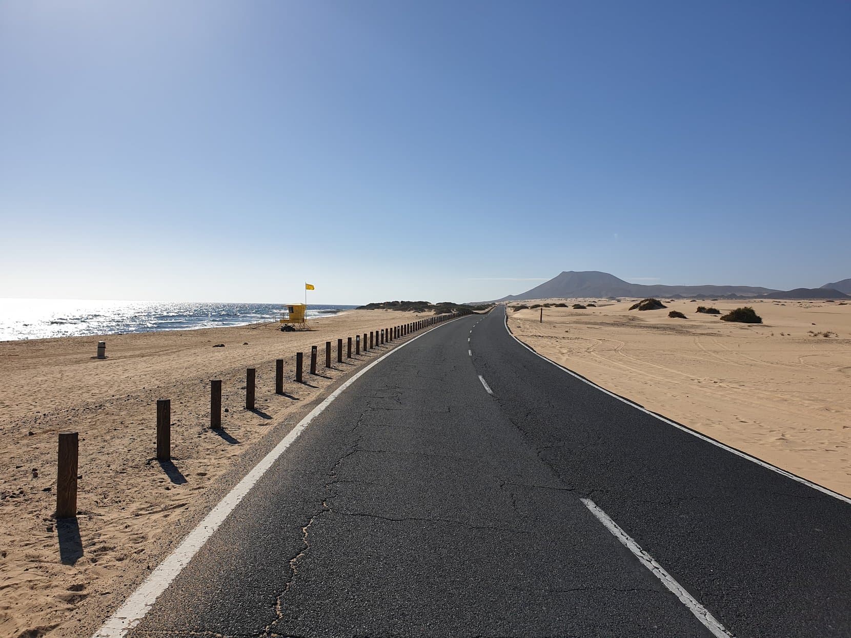 The road running through the Corralejo dunes toward a volcano cone, Fuerteventura