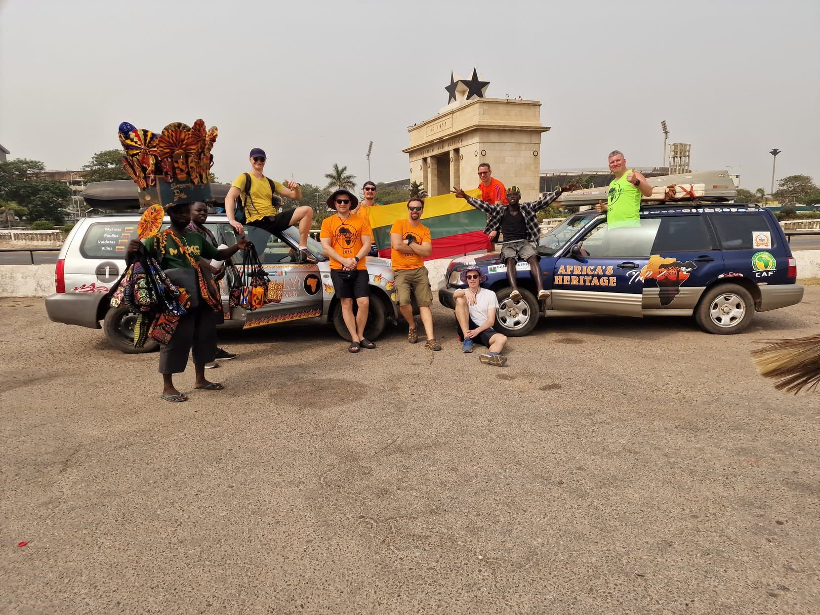 The rally crew and two decal-covered cars in front of the Black Star Gate, Accra, Ghana