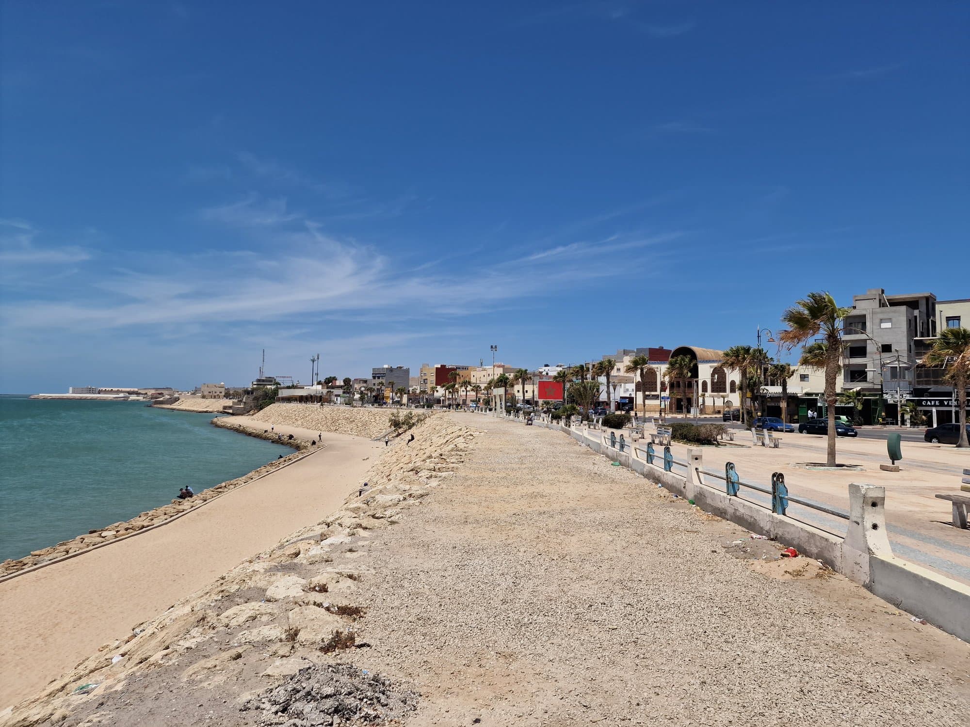 Dakhla's stone seafront promenade curving along the turquoise bay toward town