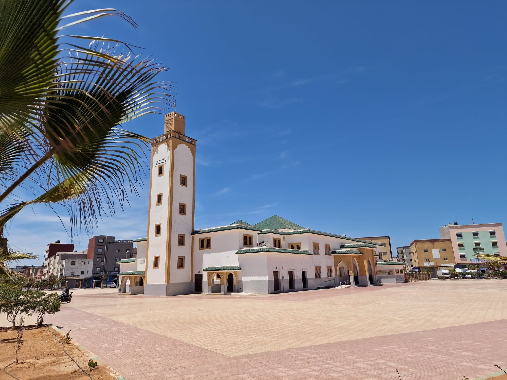 A white mosque and minaret above a quiet square in Dakhla