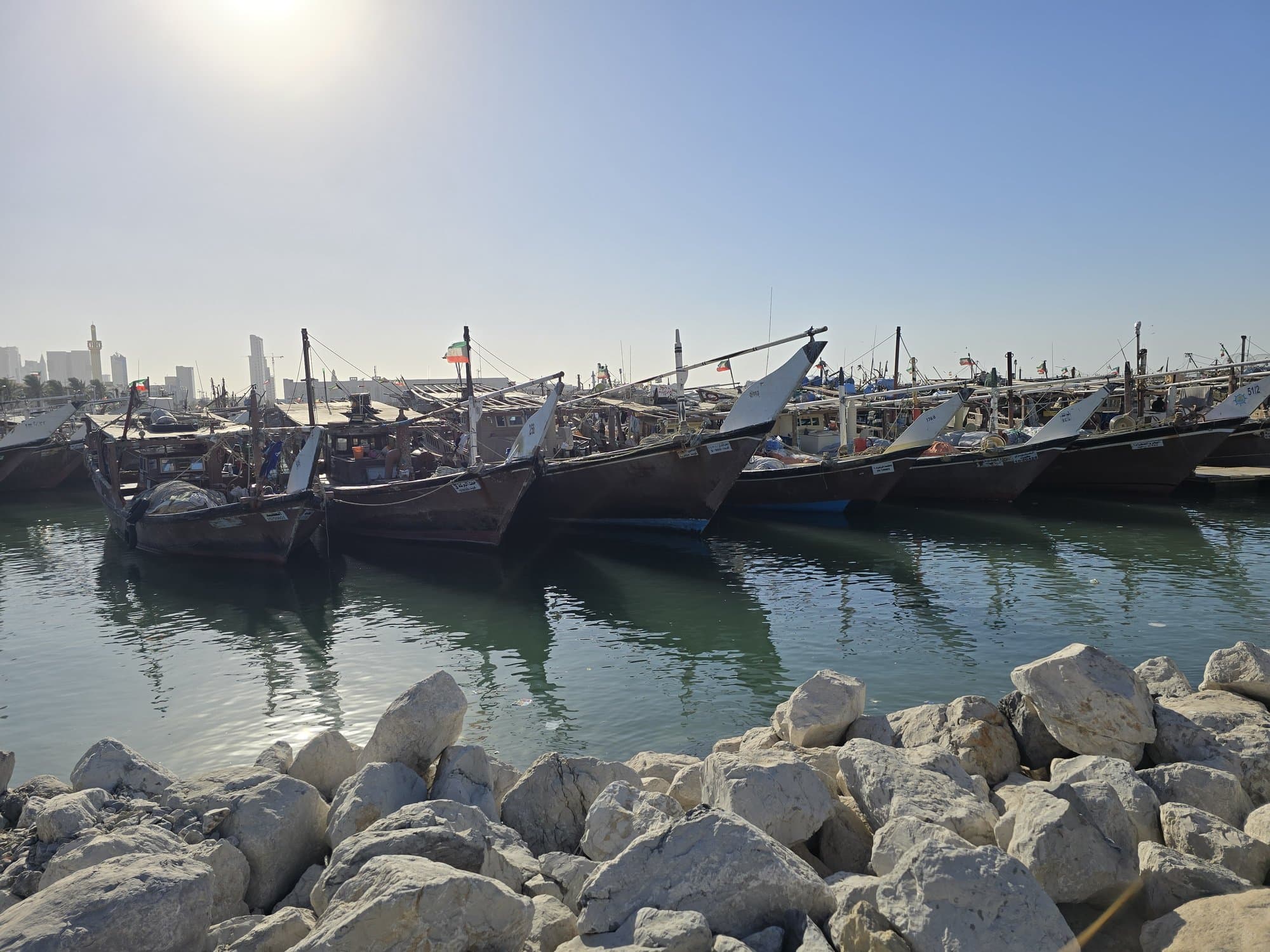 Wooden dhows moored hull to hull at the dhow harbour, white rocks in the foreground