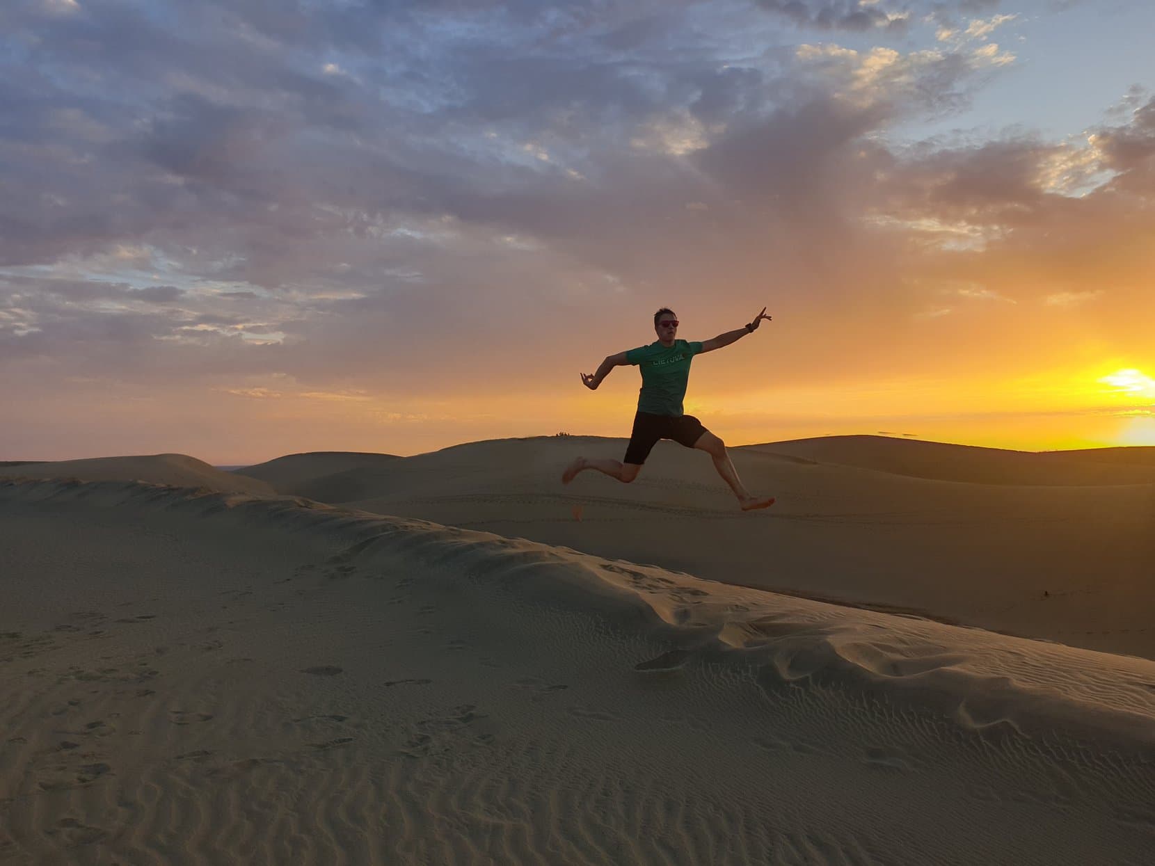 The founder mid-jump on a Maspalomas dune crest at sunset, Gran Canaria