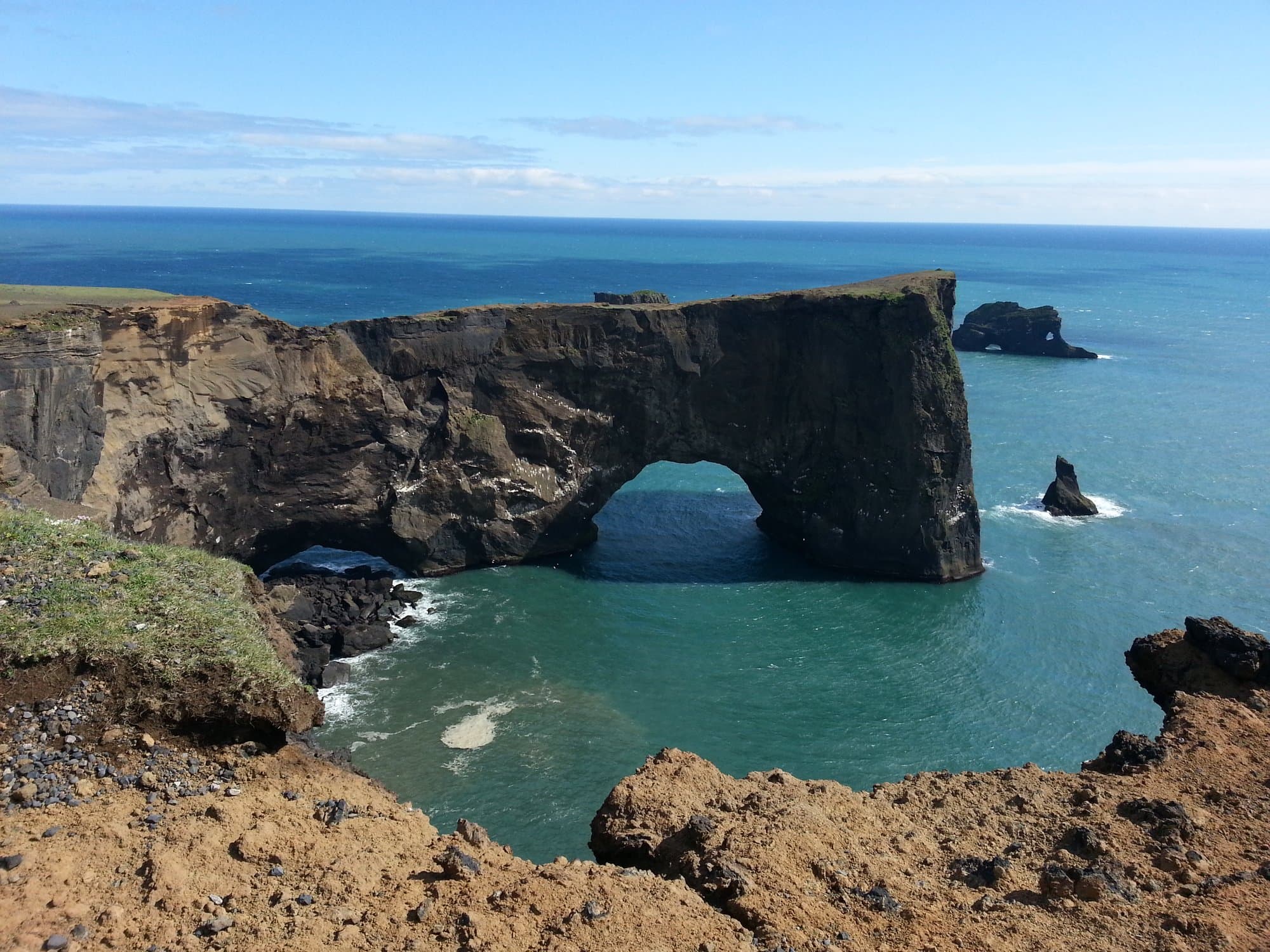 The stone arch at Dyrhólaey with black beach stretching away behind it
