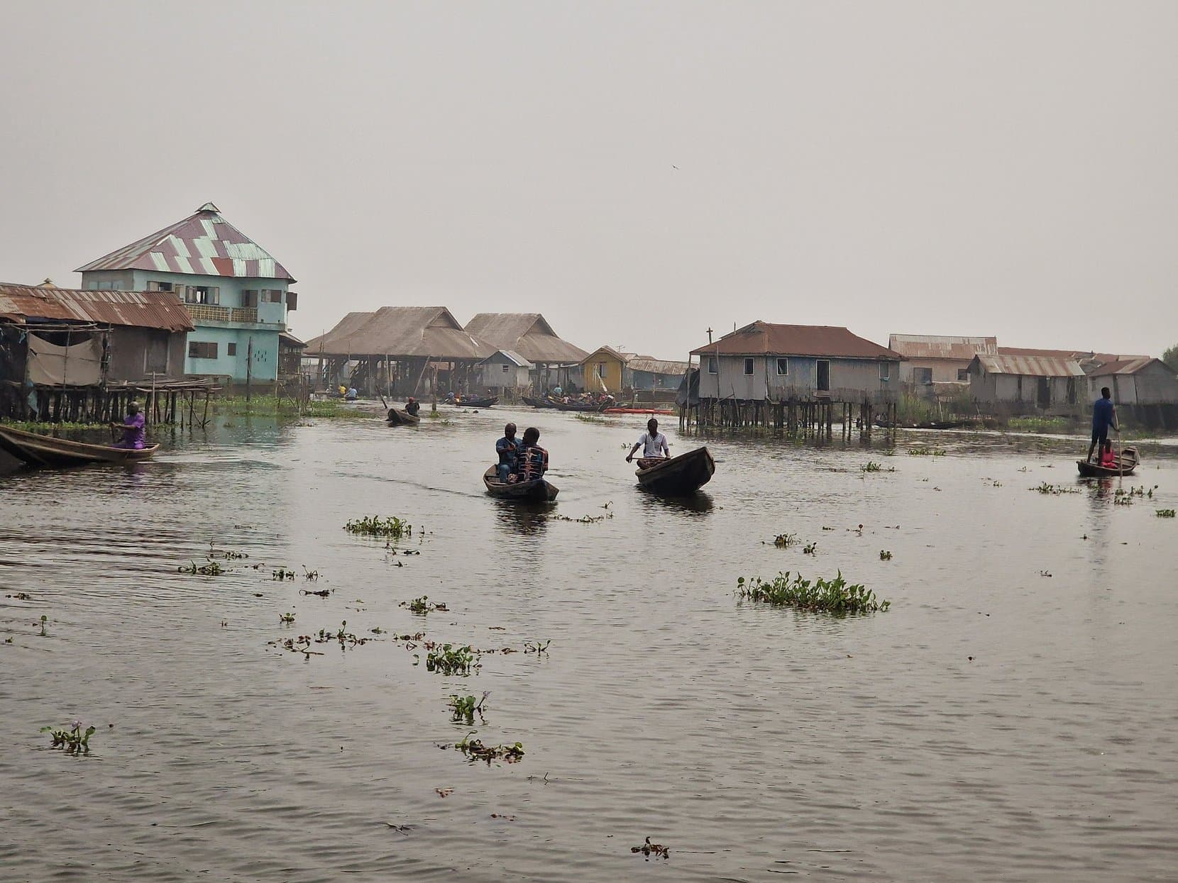 Stilt houses on the lagoon with paddlers passing on the open water at Ganvié, Benin