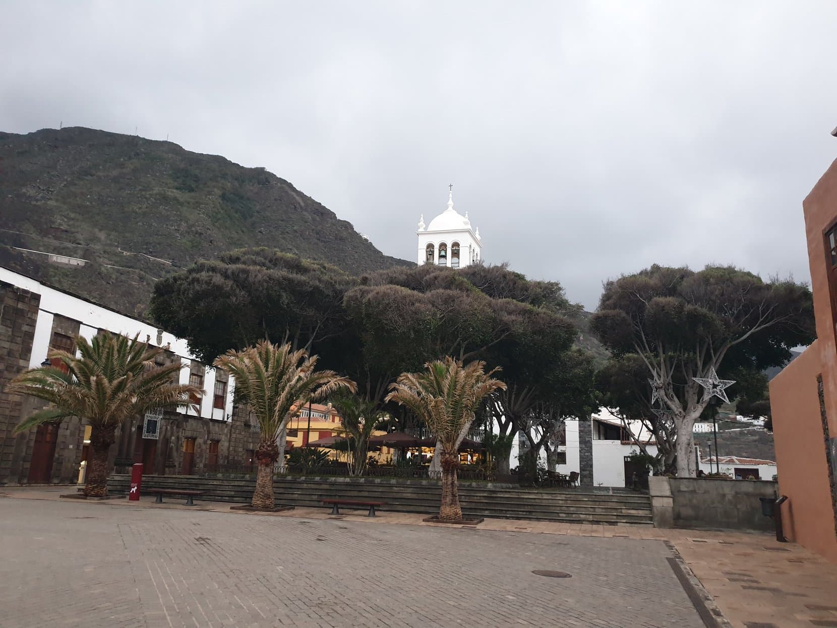 Garachico's plaza with palms and old trees in front of the church tower, Tenerife