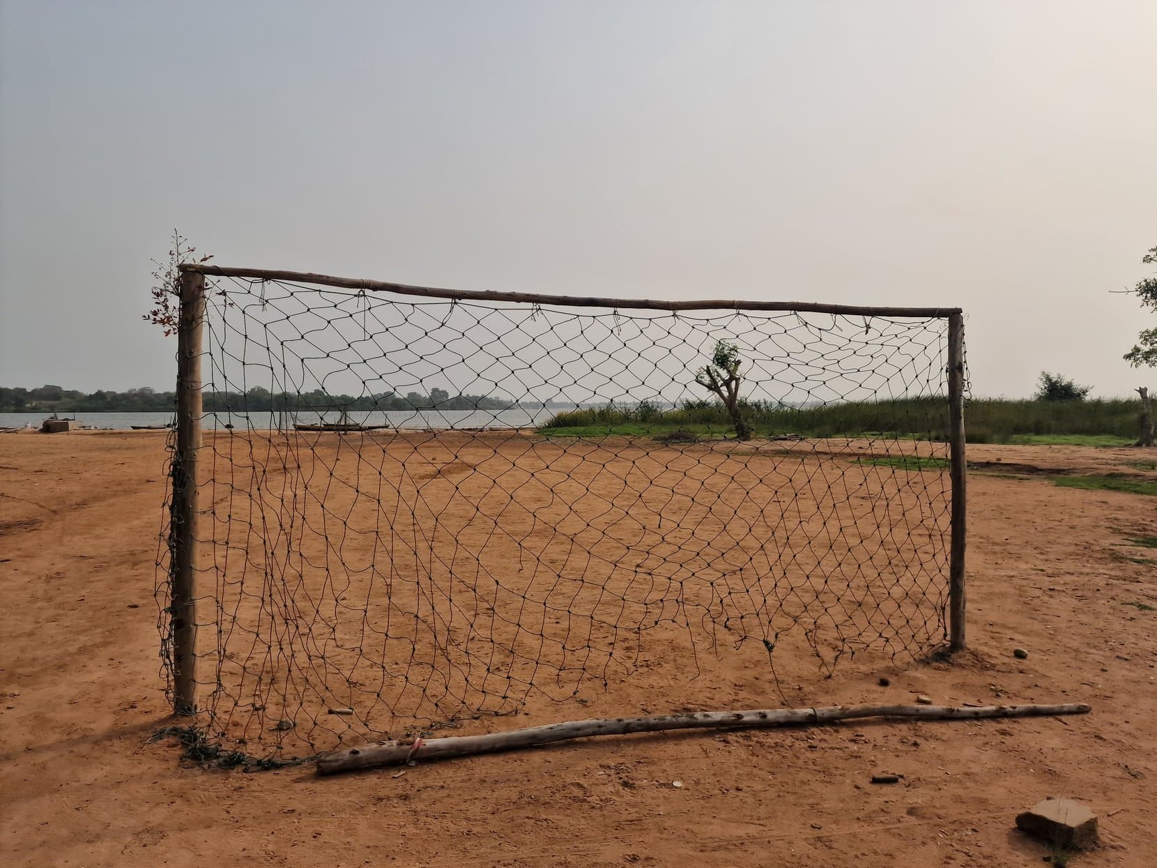 A football goal with a torn net on the sand beside Lake Togo, Togoville, Togo