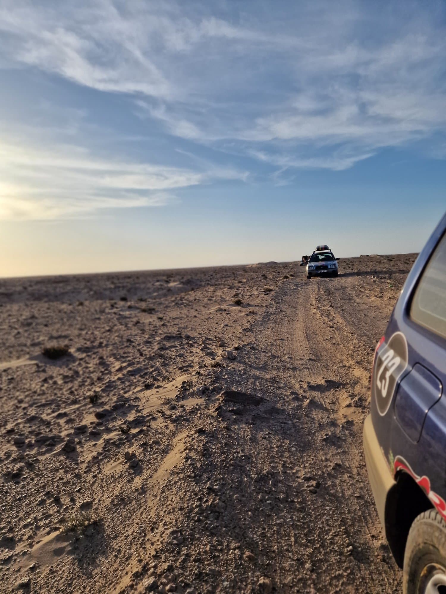 A car climbing a desert track at golden hour