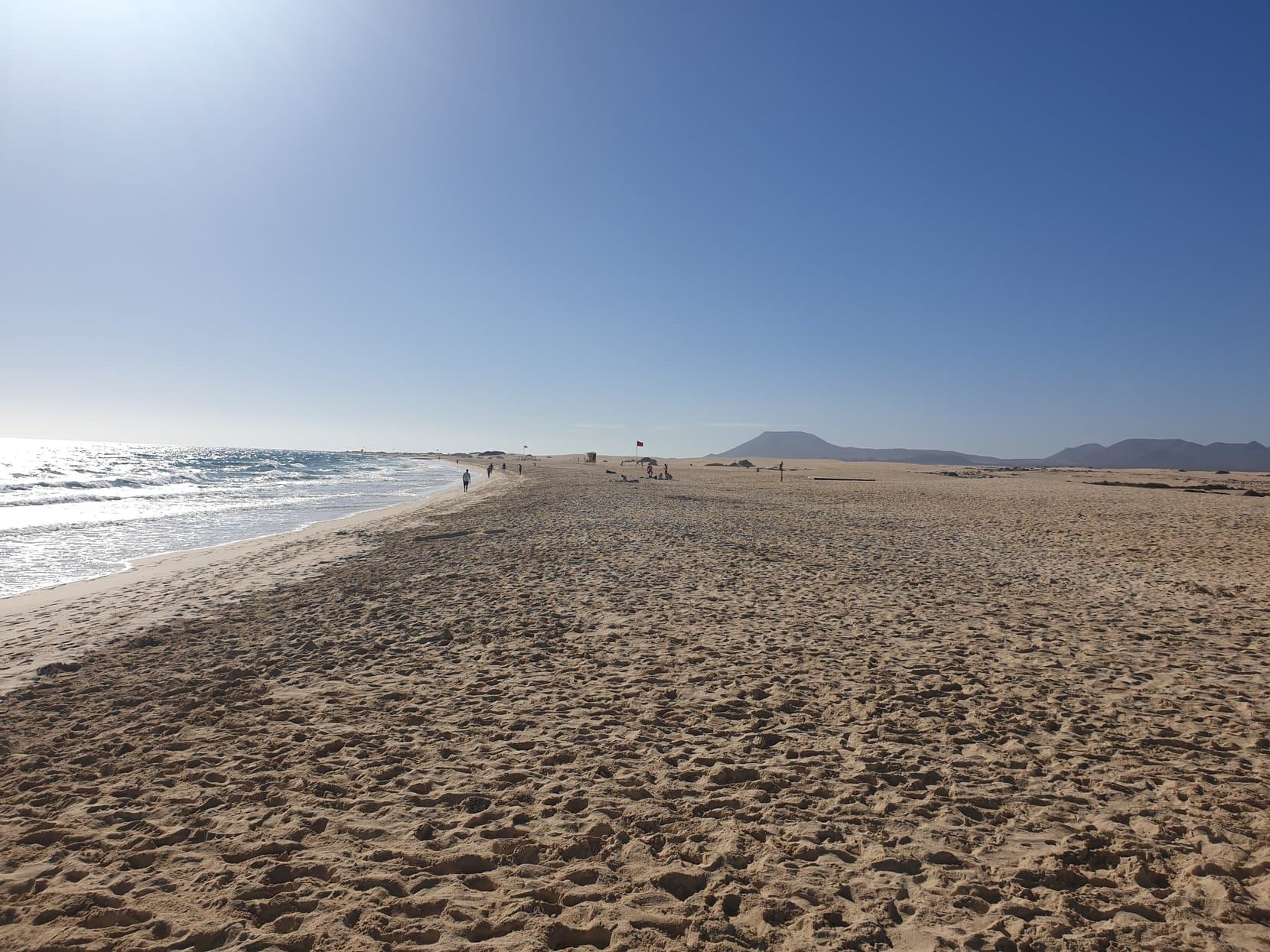 The white sand of Grandes Playas running empty toward a volcano cone, Corralejo, Fuerteventura