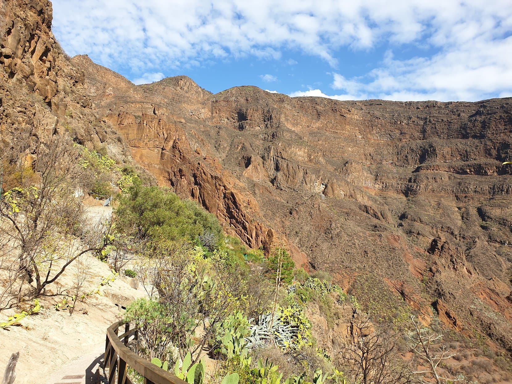 The steep red walls of the Guayadeque ravine above a railed path, cactus on the slope, Gran Canaria