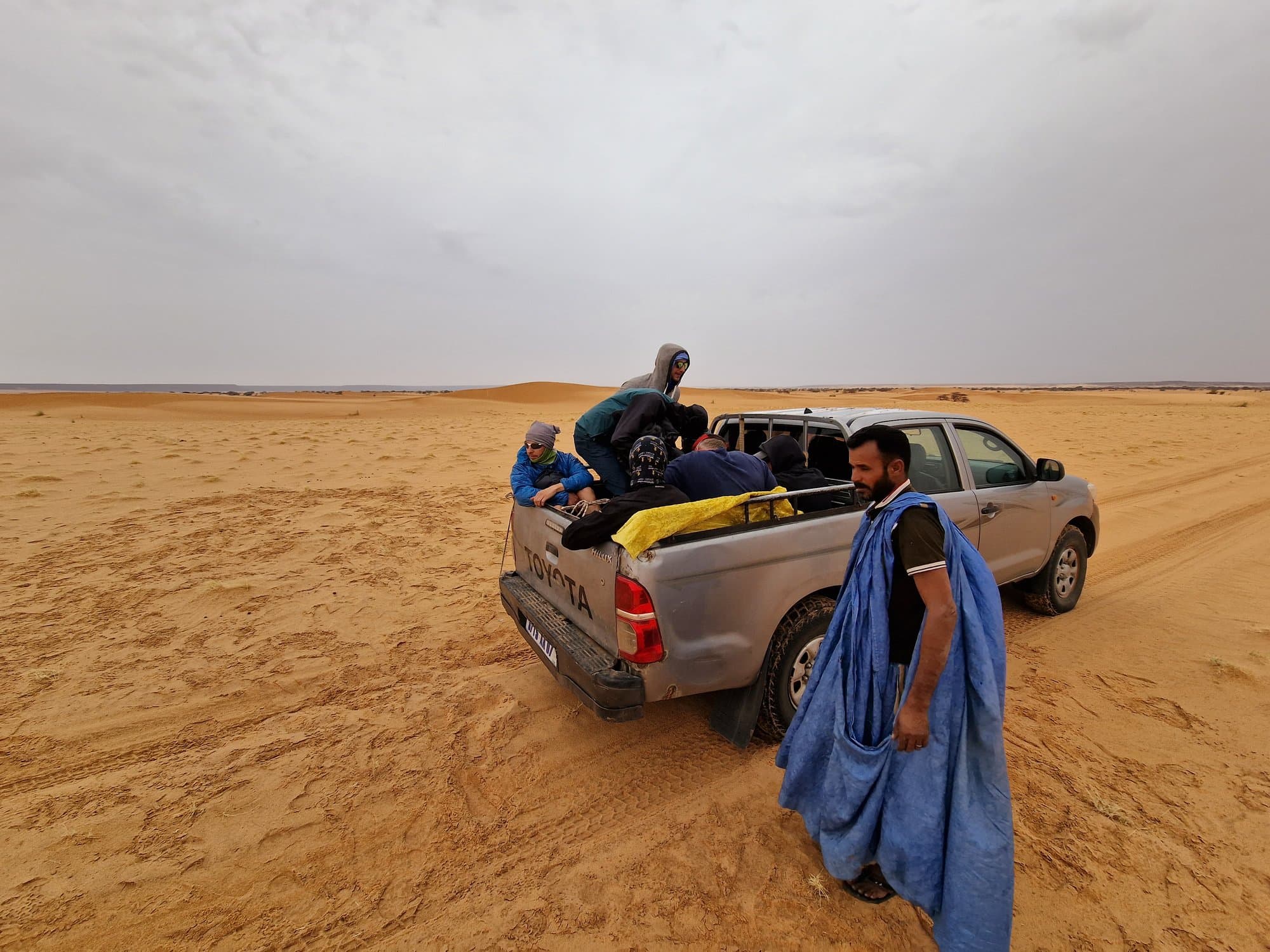 The crew riding in the open bed of a Hilux in the desert