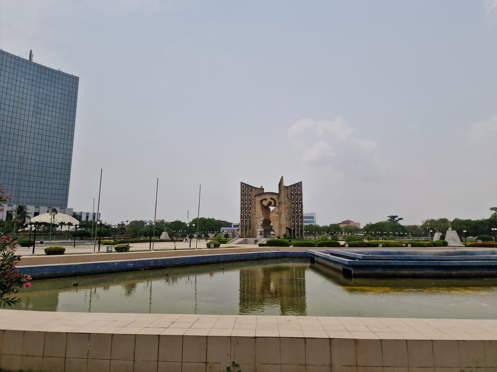 The Independence Monument and its reflecting pool with a tower behind, Lomé, Togo