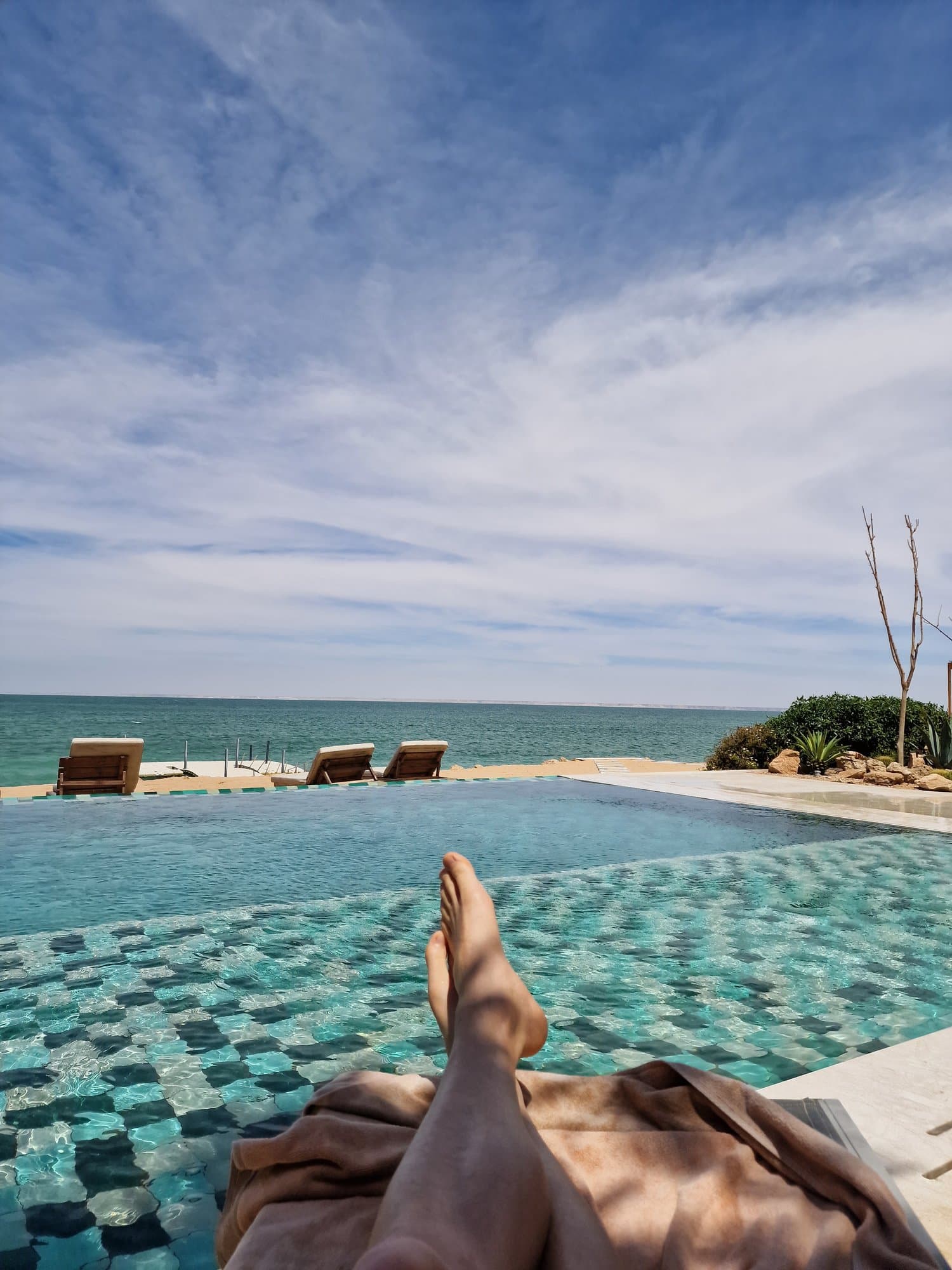 Feet up at an infinity pool overlooking the turquoise lagoon
