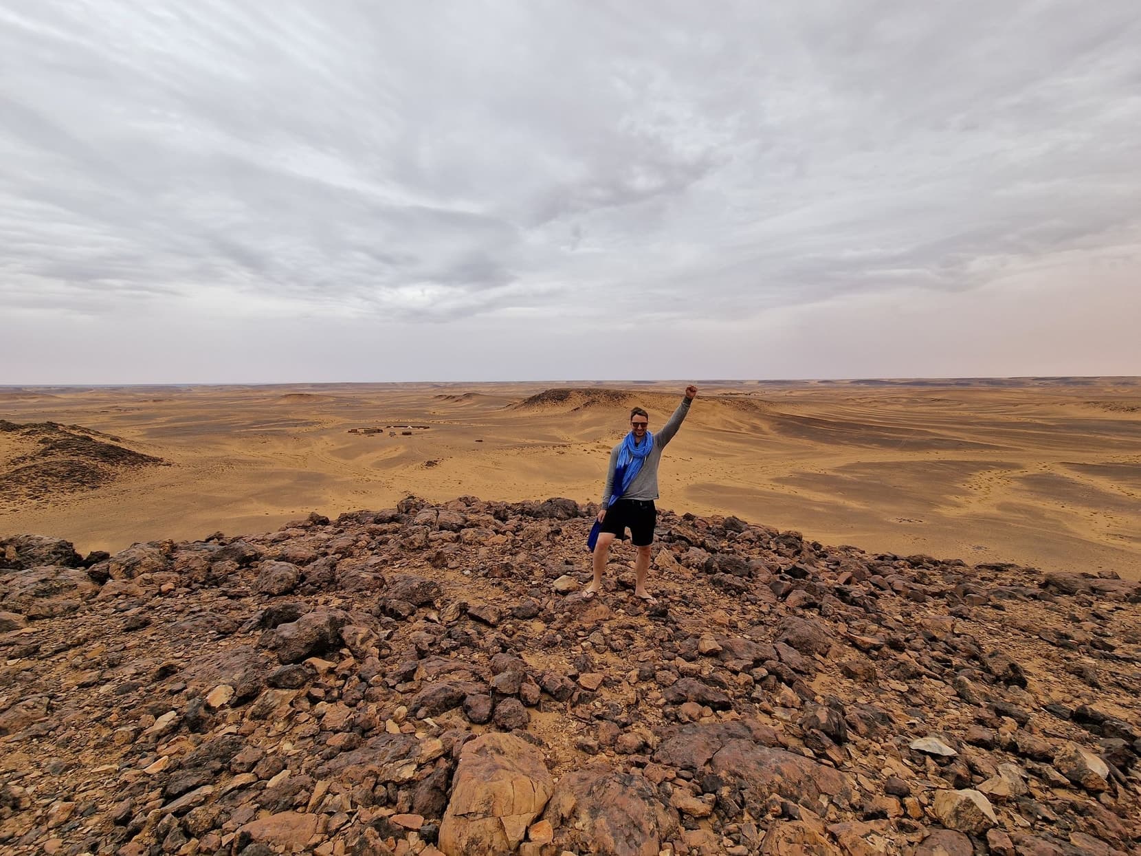 A lone figure on a black-rock ridge inside the Richat Structure