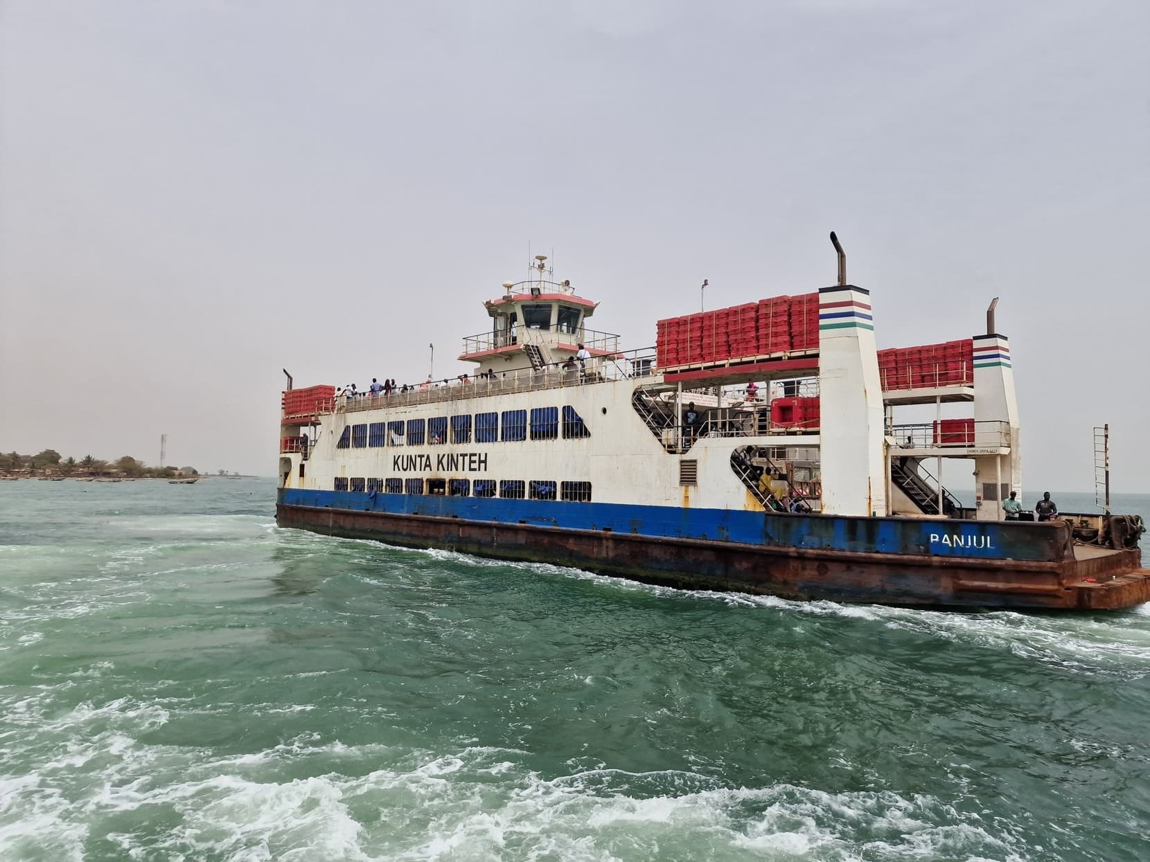 The Kunta Kinteh ferry crossing the green water of the Gambia River mouth