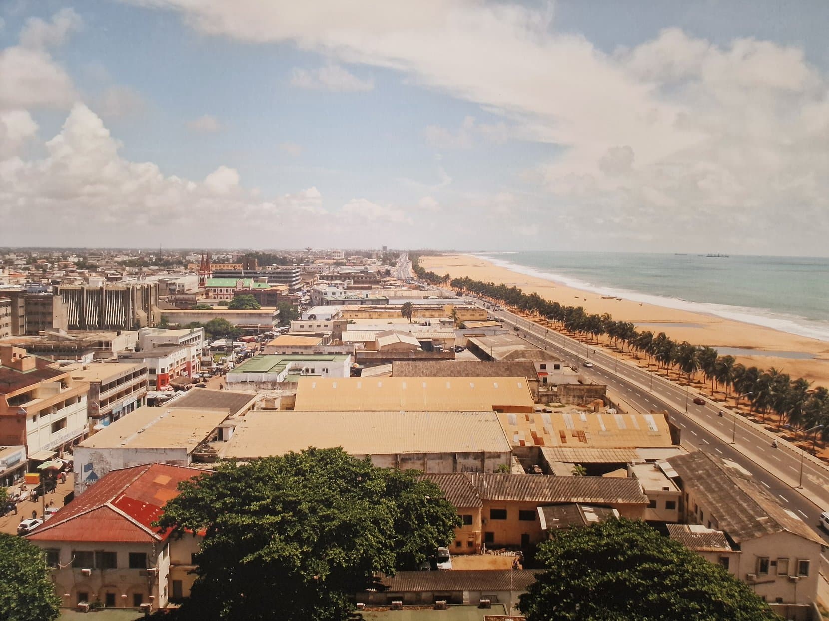 Lomé's low rooftops and the long beach beside the city, seen from above, Togo