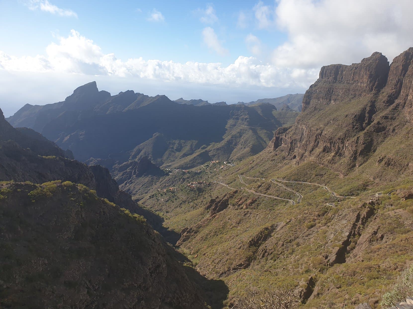 The Masca gorge falling away to the sea, with the switchback road stitched across its wall, Tenerife