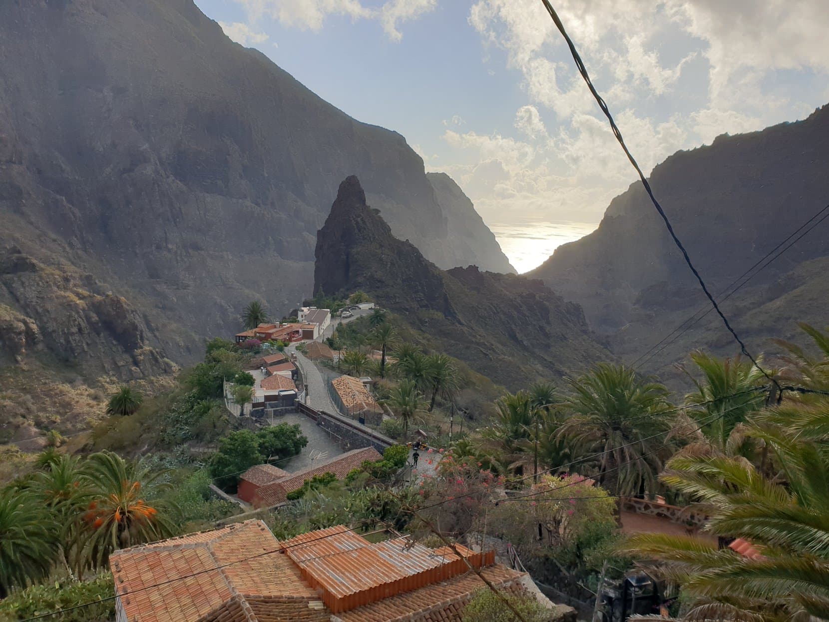 The rooftops of Masca village under its rock spire, with the gorge falling to a silver sea, Tenerife