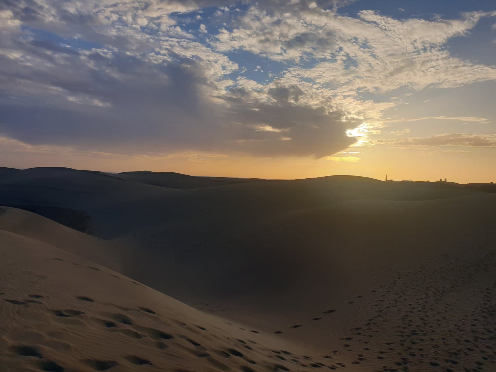 Sunset over the dune ridges of Maspalomas with the lighthouse on the horizon, Gran Canaria