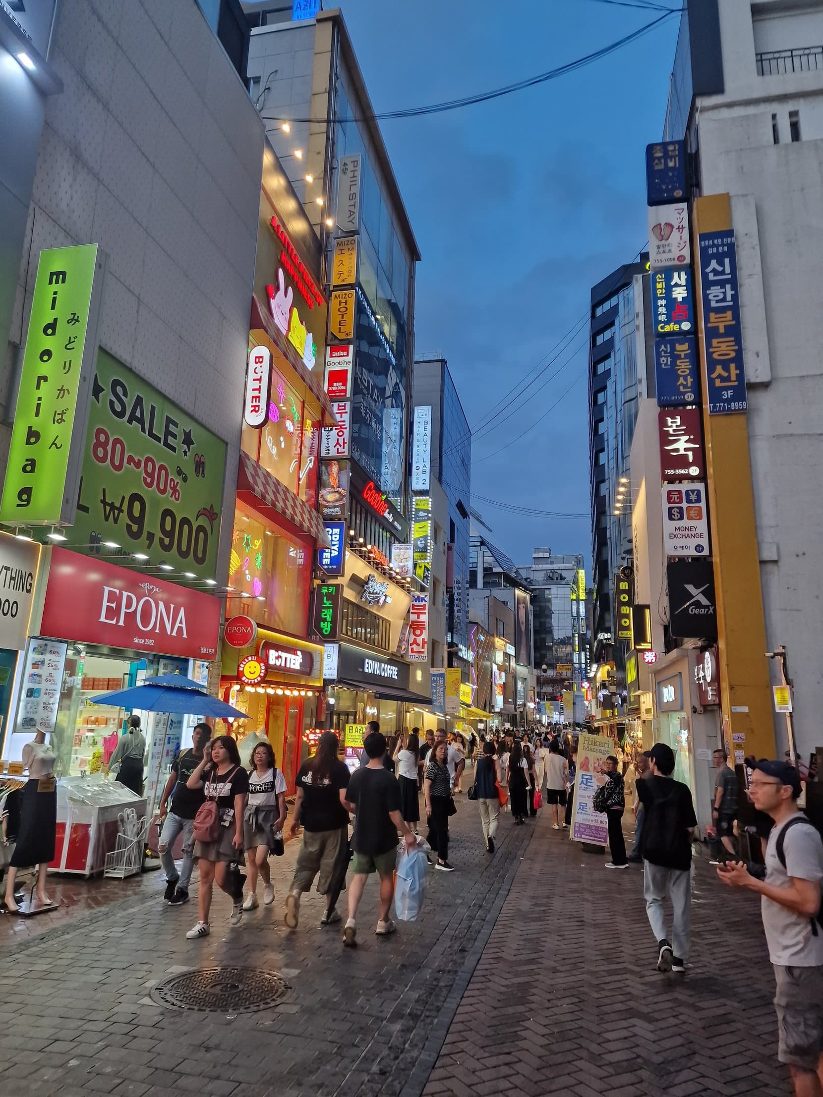 Myeongdong shopping street at dusk with lit signs and crowds, Seoul