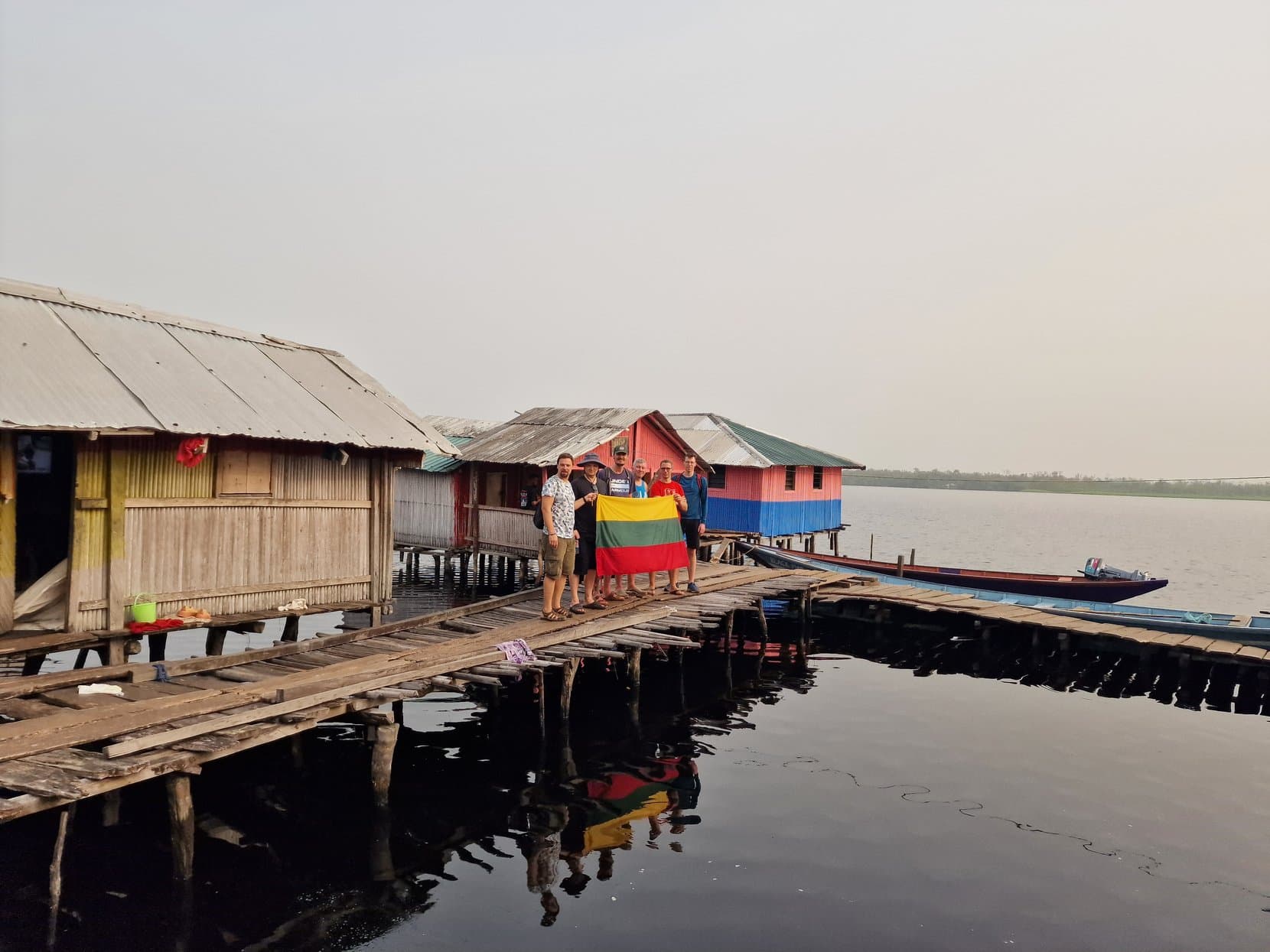 A timber boardwalk between painted stilt houses with the open lake beyond, Nzulezo, Ghana