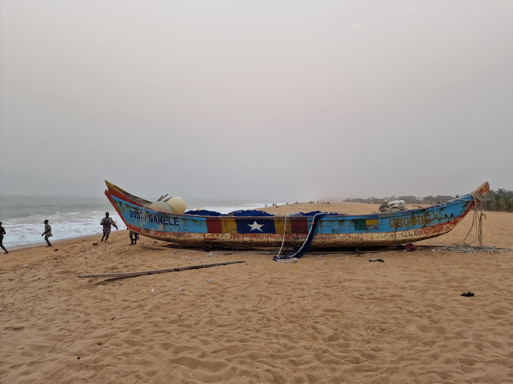 A painted wooden fishing pirogue hauled up on the sand of the beach west of Cotonou, Benin