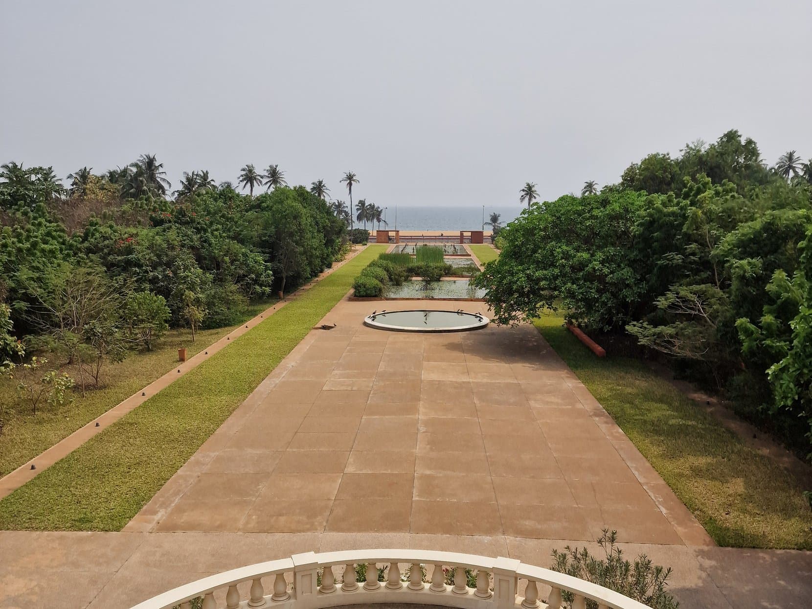 A long lawn and pool running from a balustrade toward the sea in the Palais de Lomé park, Togo