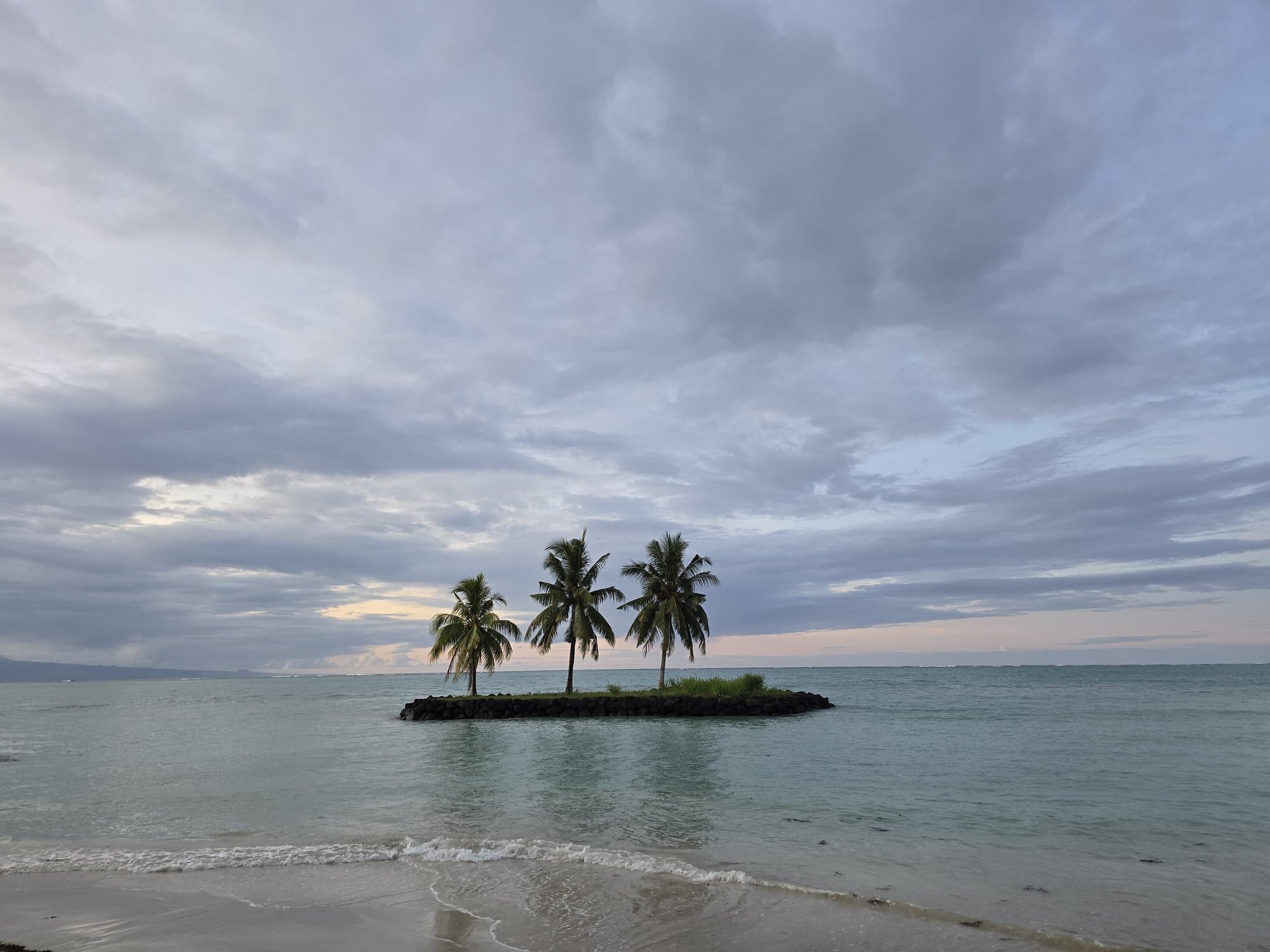 A tiny palm islet just offshore in evening light
