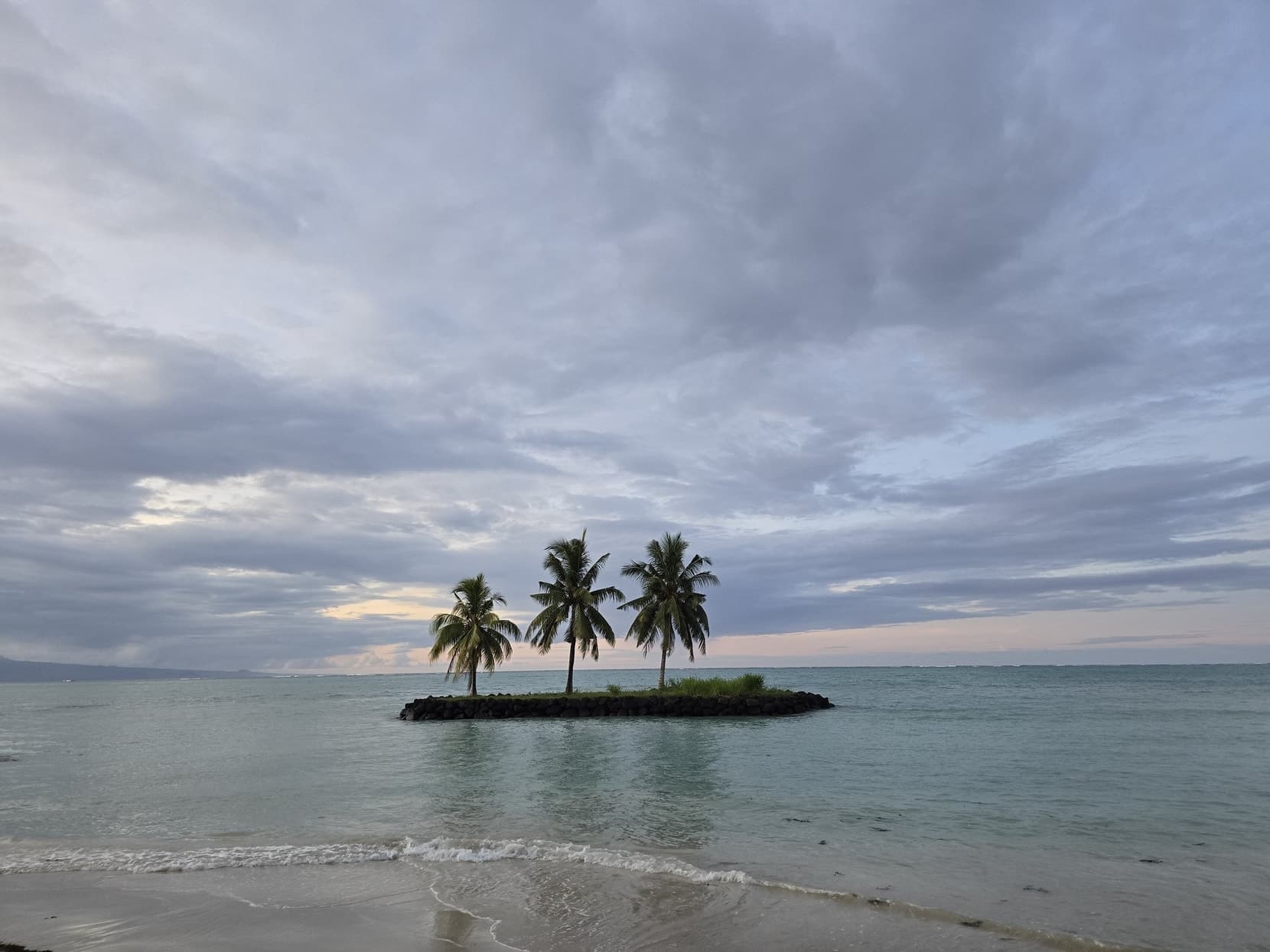 A tiny palm islet just offshore in evening light