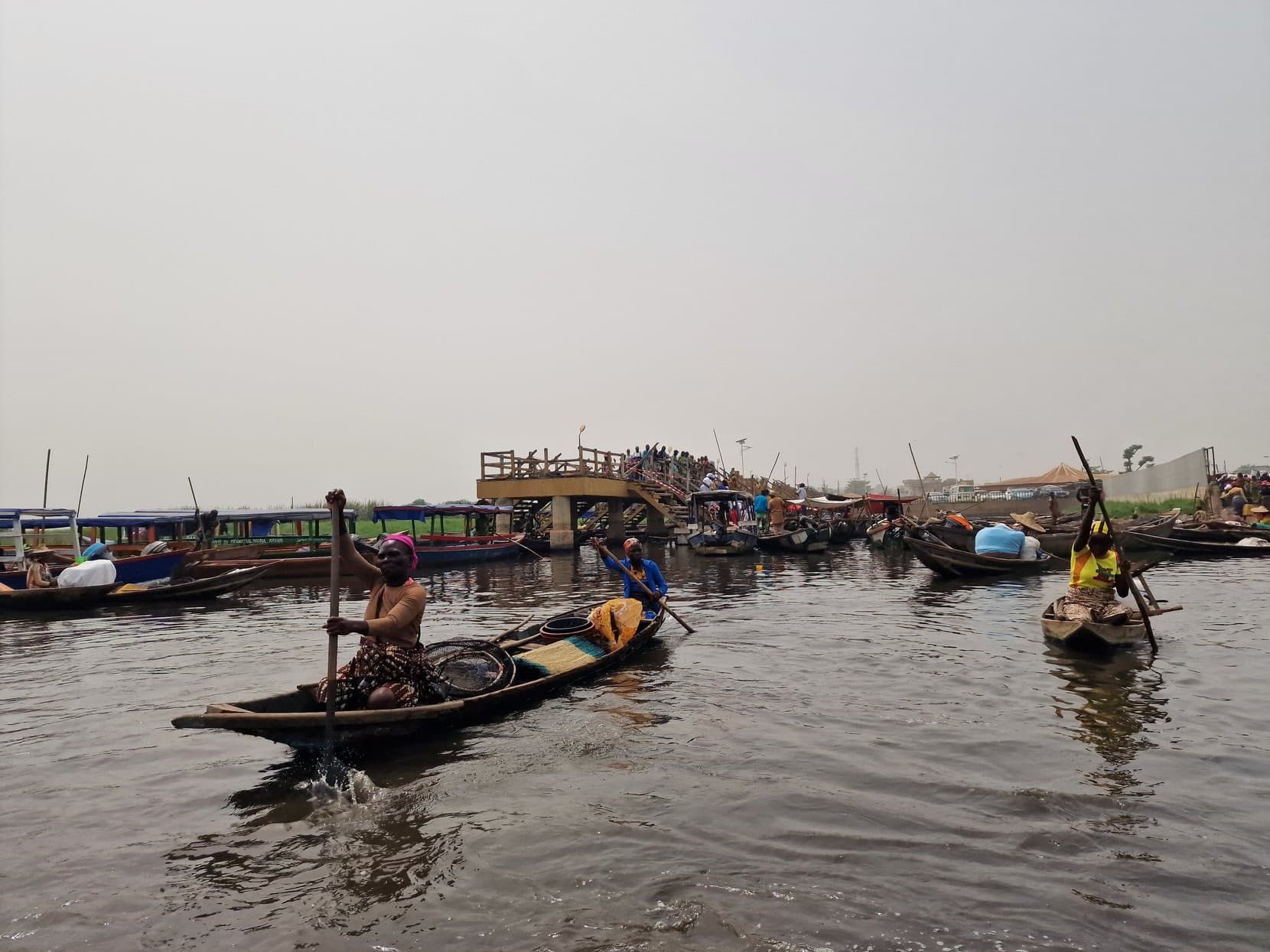 A man standing in a wooden pirogue with a long pole near the jetty at the Ganvié landing, Benin