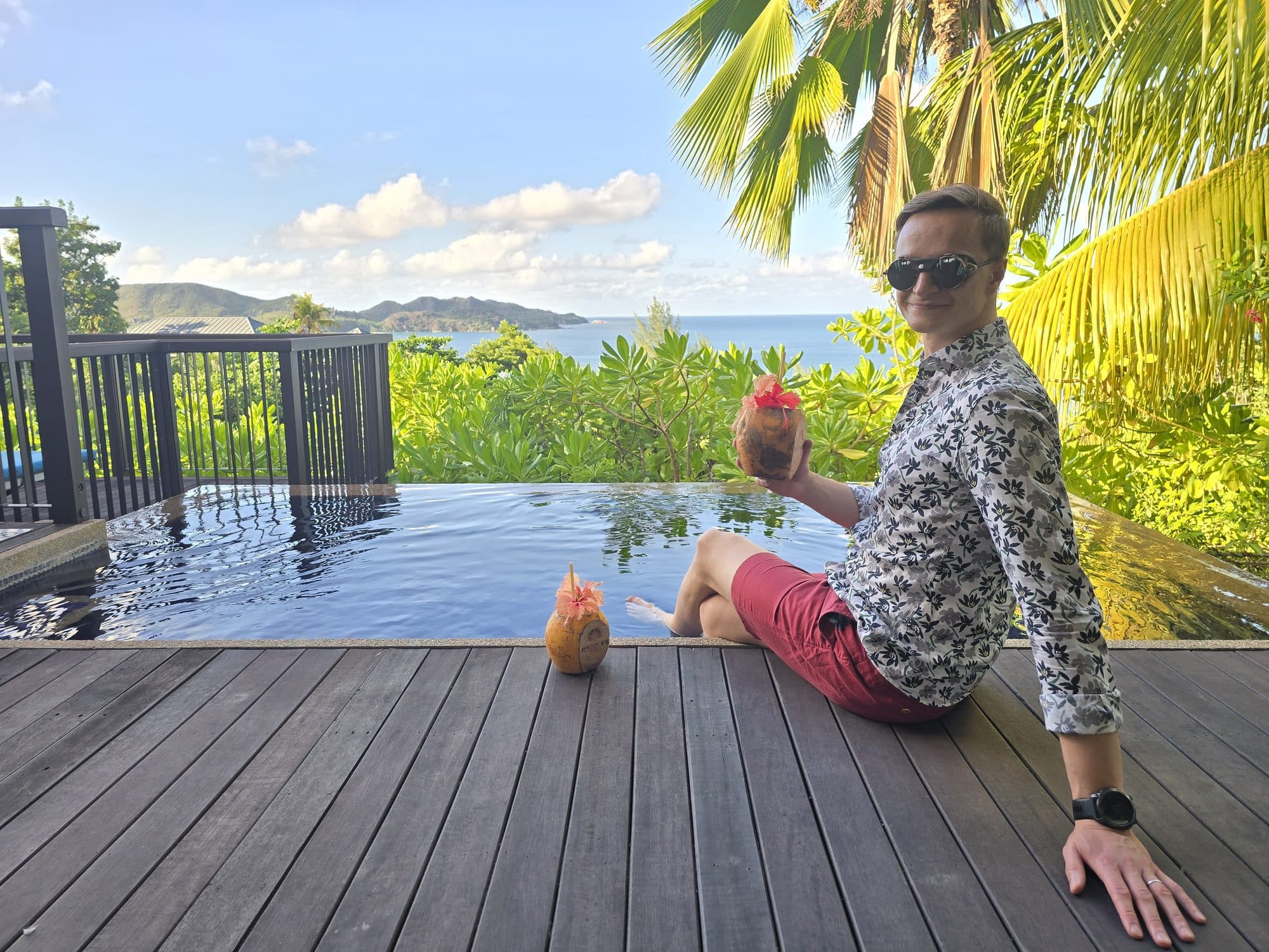 Sitting with a coconut beside an infinity pool above the sea, Praslin, Seychelles