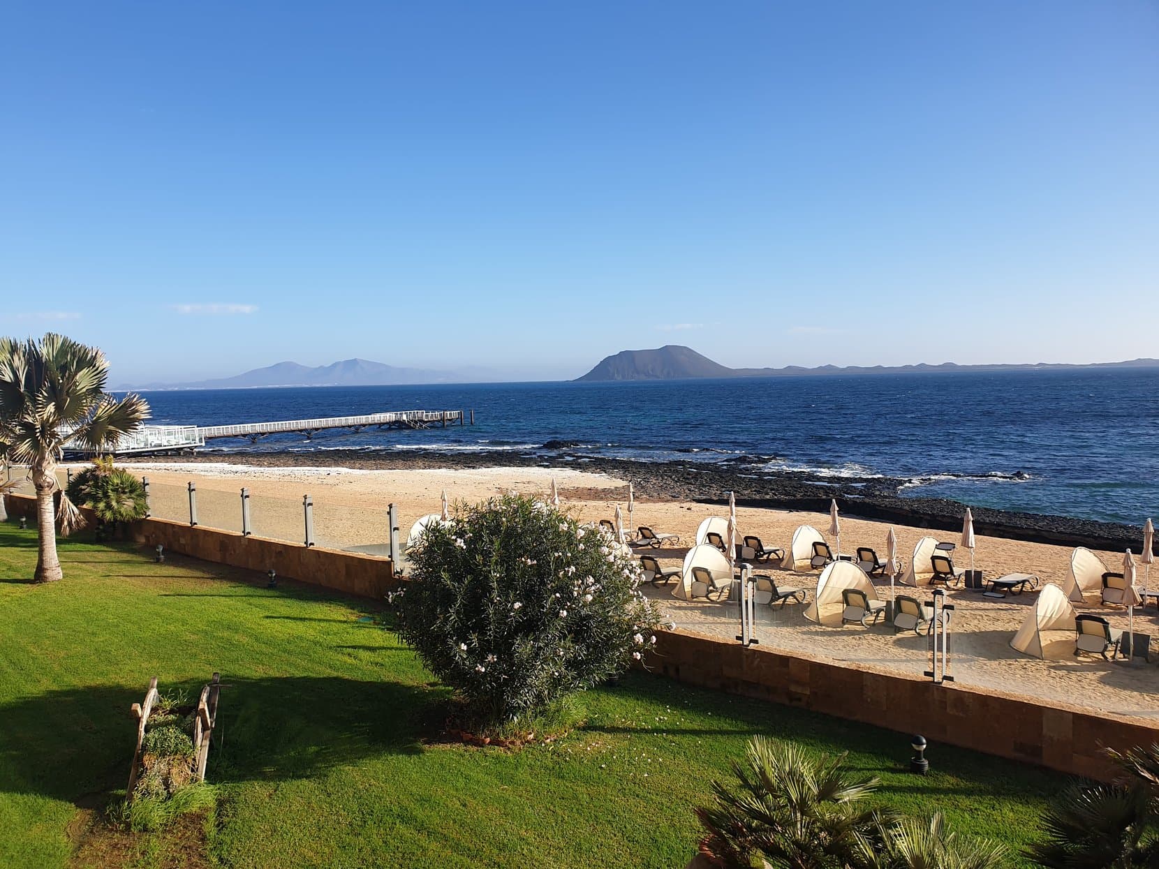 Sun loungers by the sea wall on a Corralejo resort morning, Fuerteventura