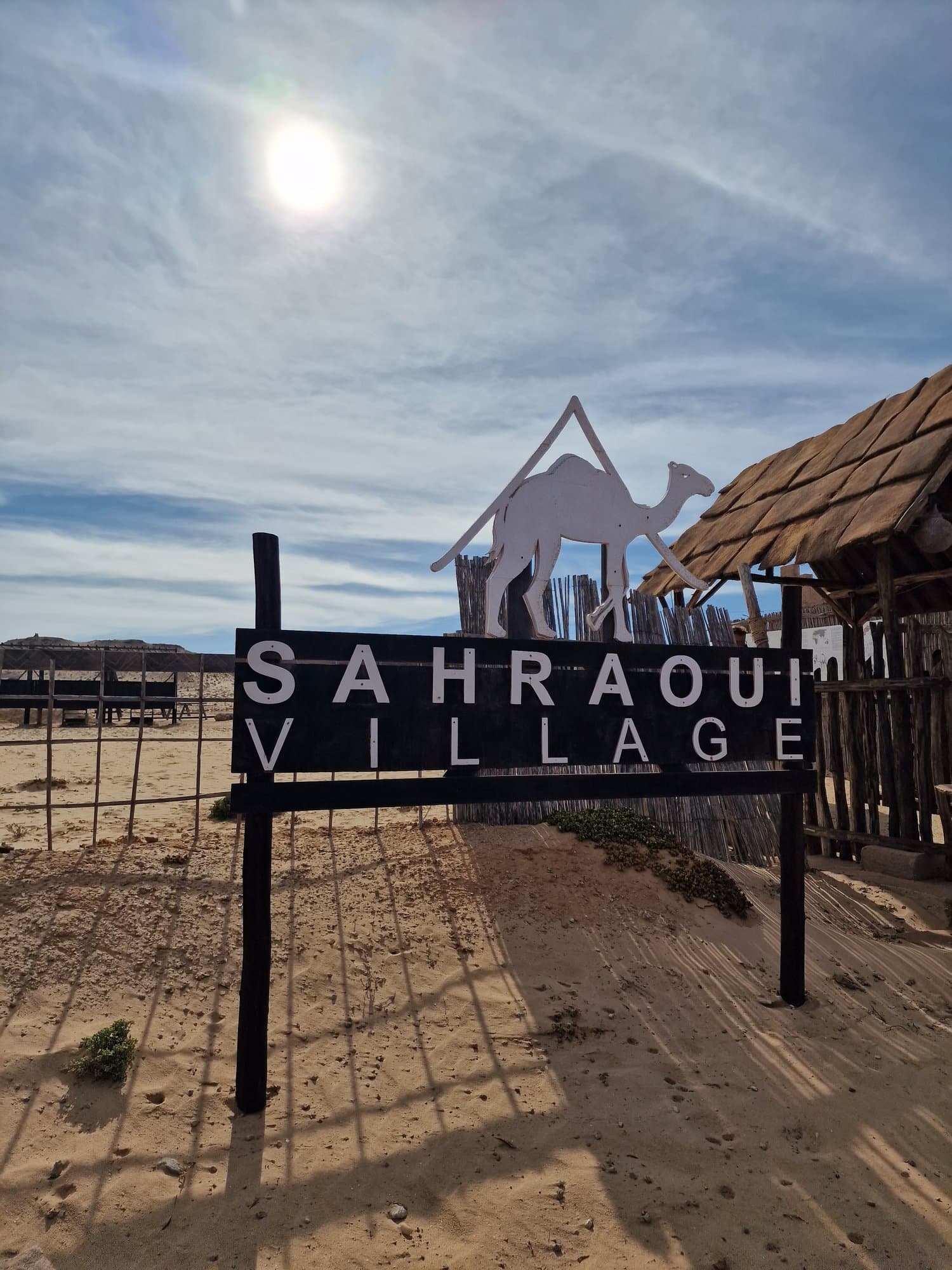 The Sahraoui Village sign with a camel silhouette in the dunes
