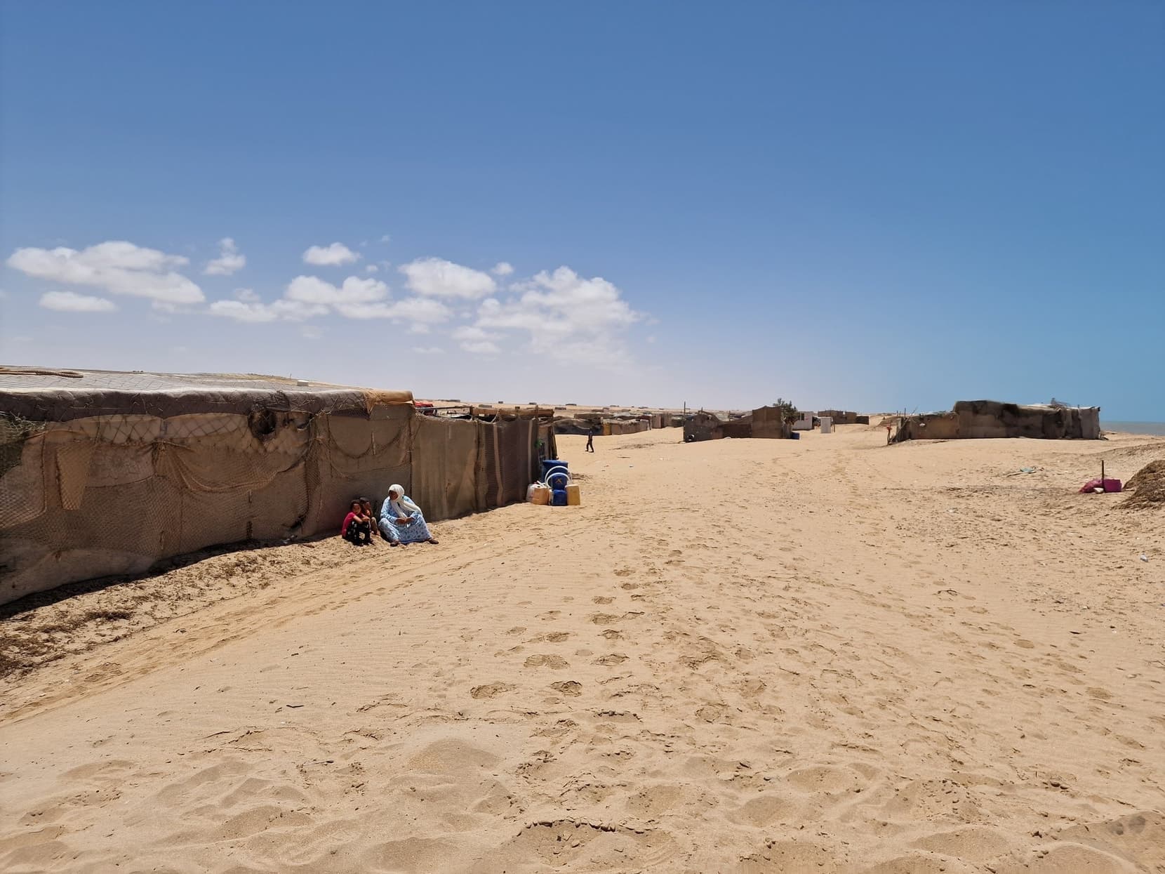 A sand track running past Sahrawi tents toward the beach