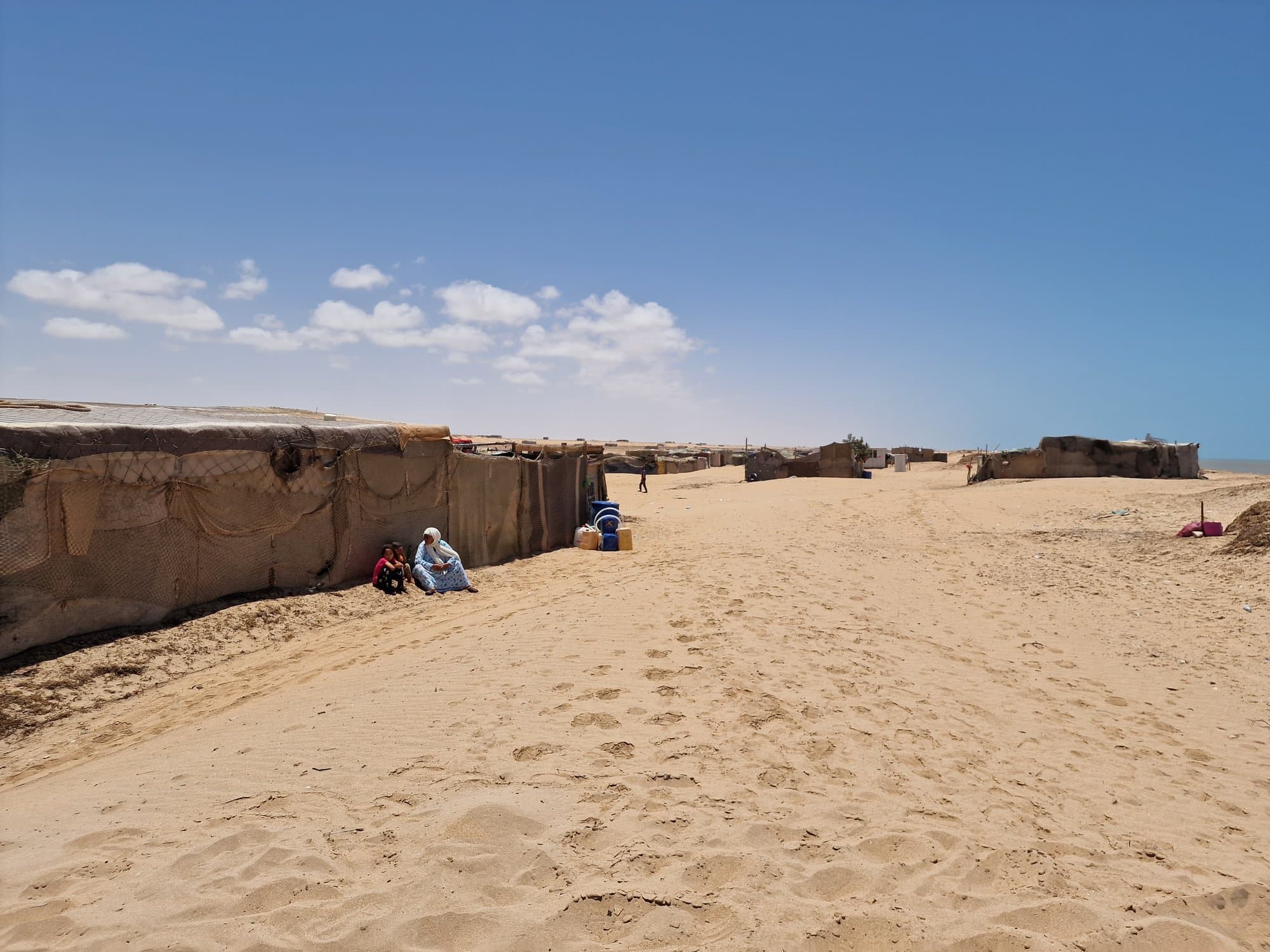 A sand track running past Sahrawi tents toward the beach