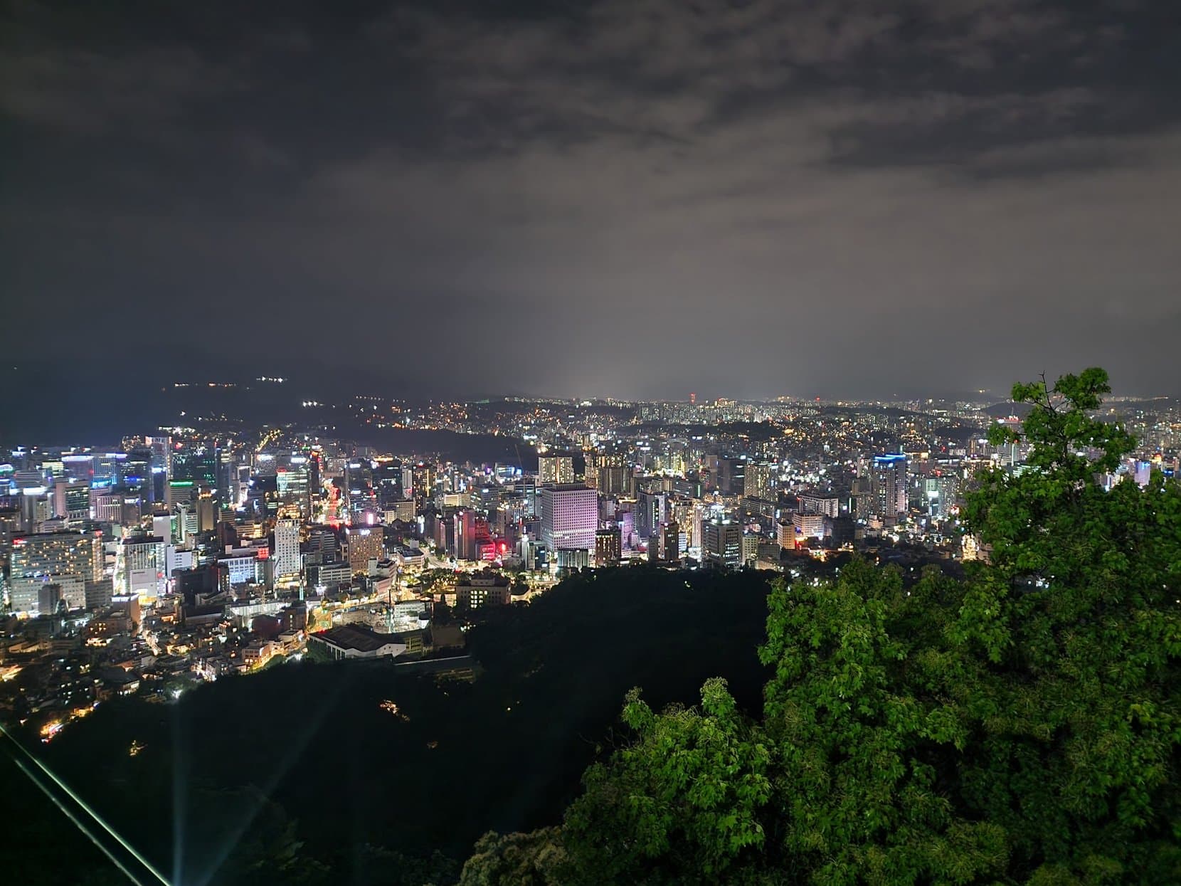 Seoul at night from Namsan, city lights running to the horizon under a cloudy sky, South Korea
