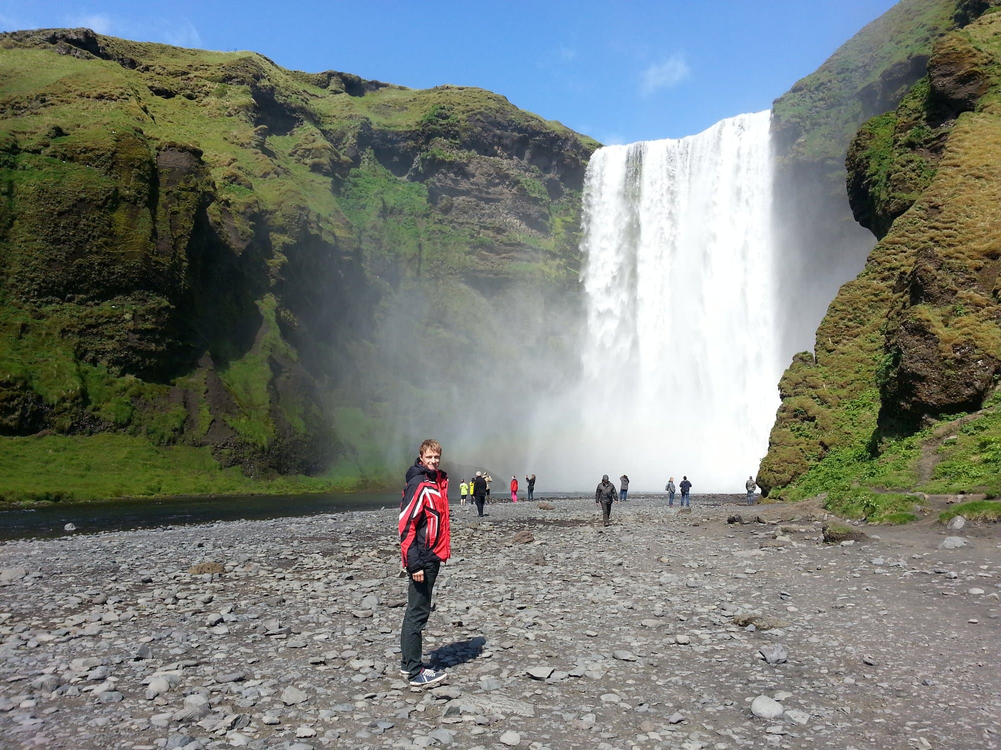 Skógafoss dropping sixty metres with people small at its base, south Iceland