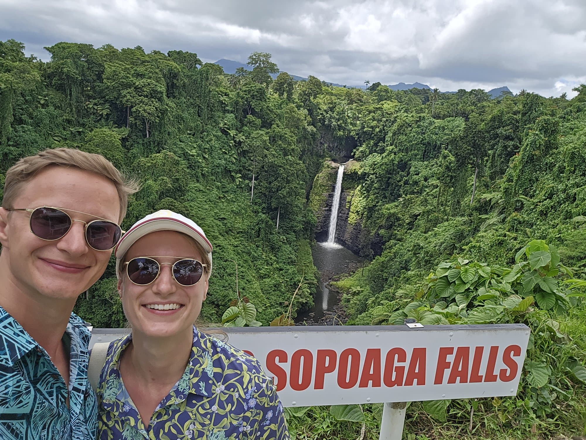 Two travellers at the Sopo'aga Falls sign above the gorge
